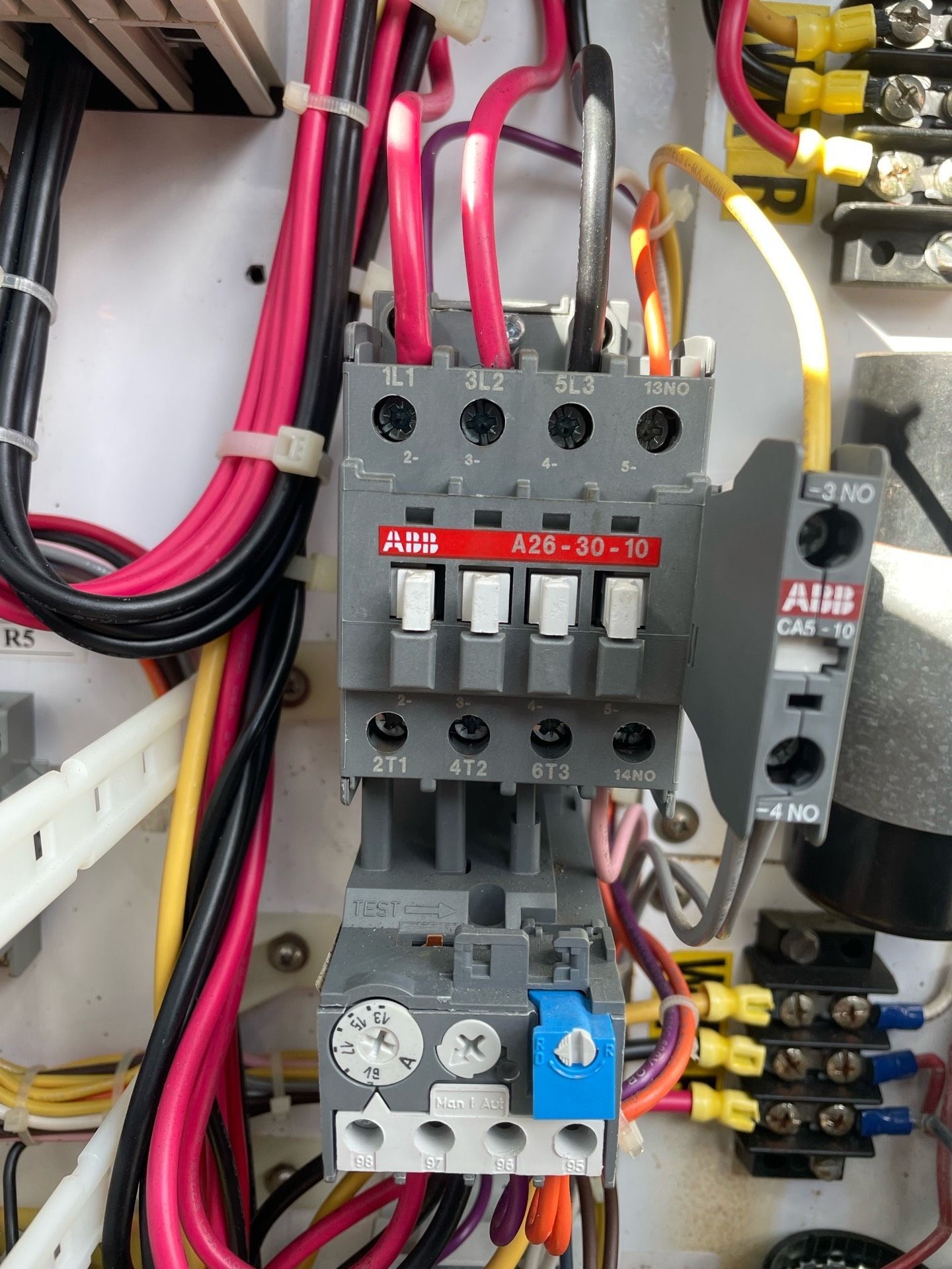 Electrician testing an outlet with a voltage tester, wearing gloves and tool belt.