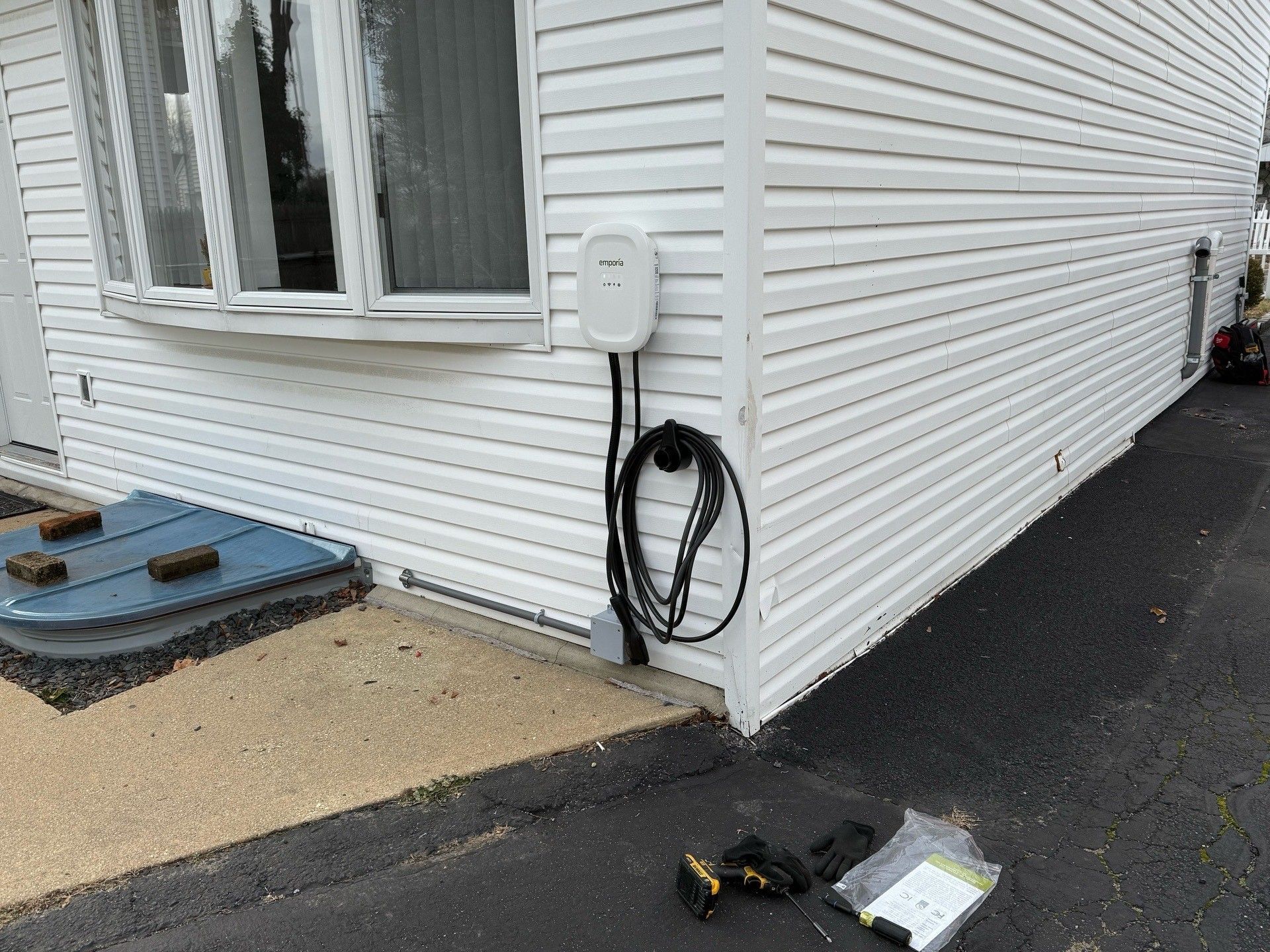 Child connecting wires to an EV charger box on a white wall, electrical hazard.