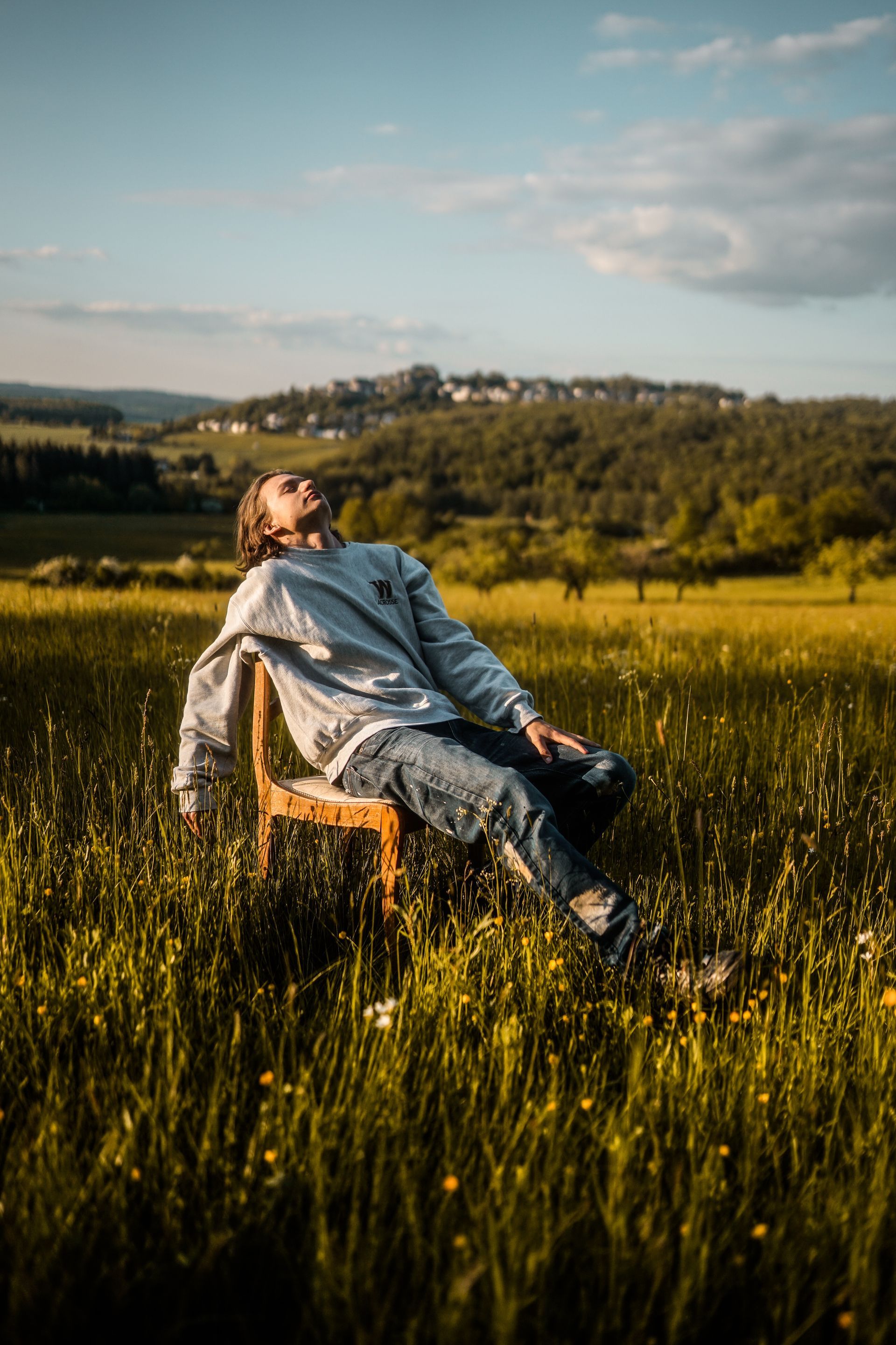 Ein Mann sitzt auf einem Holzstuhl auf einem Feld.