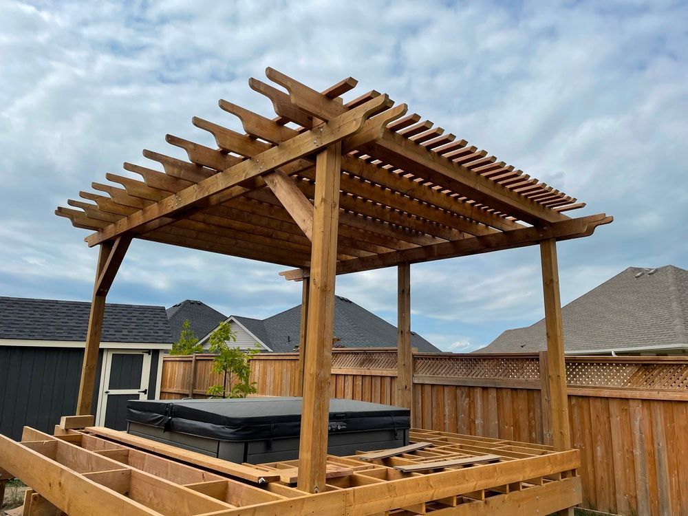 A wooden pergola with a hot tub underneath it in a backyard.