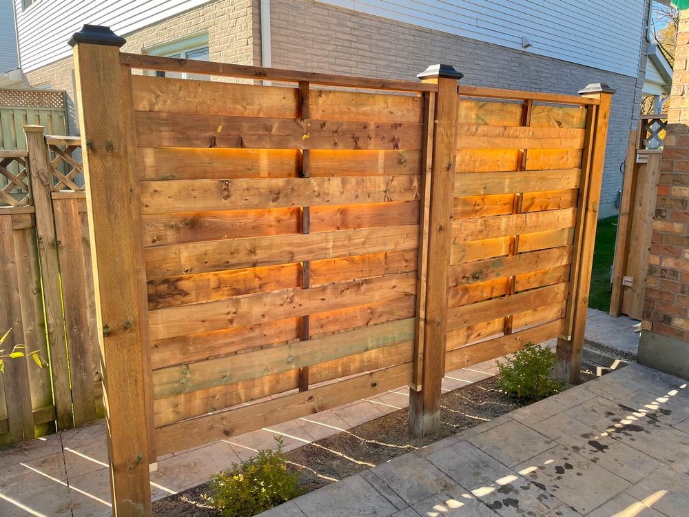 A wooden fence is sitting on a sidewalk next to a house.