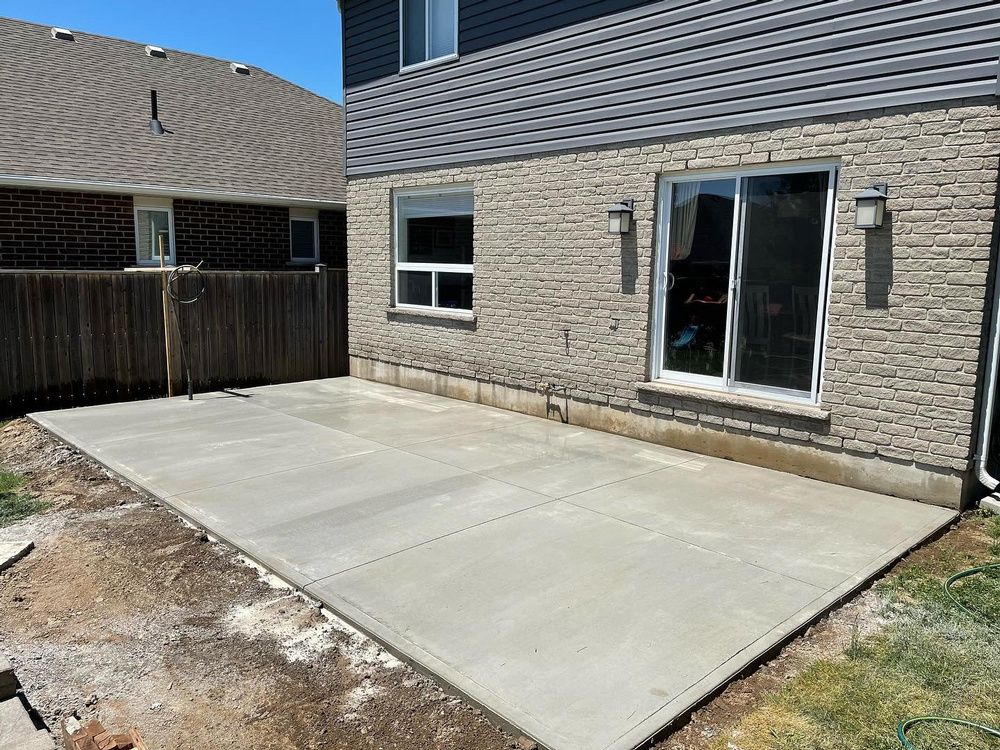 A concrete patio is being built in front of a brick house.