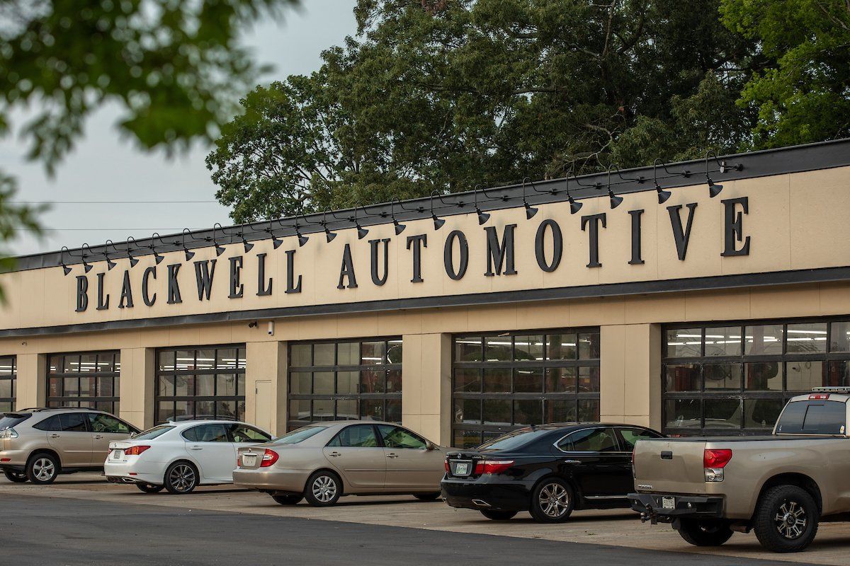 A row of cars are parked in front of a building that says blackwell automotive.