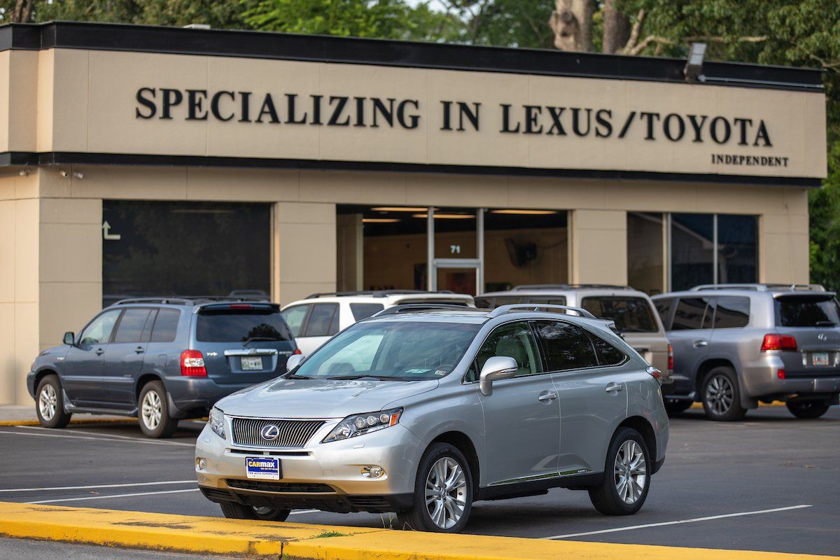 Silver Lexus parked in front of an automotive shop with a sign reading 