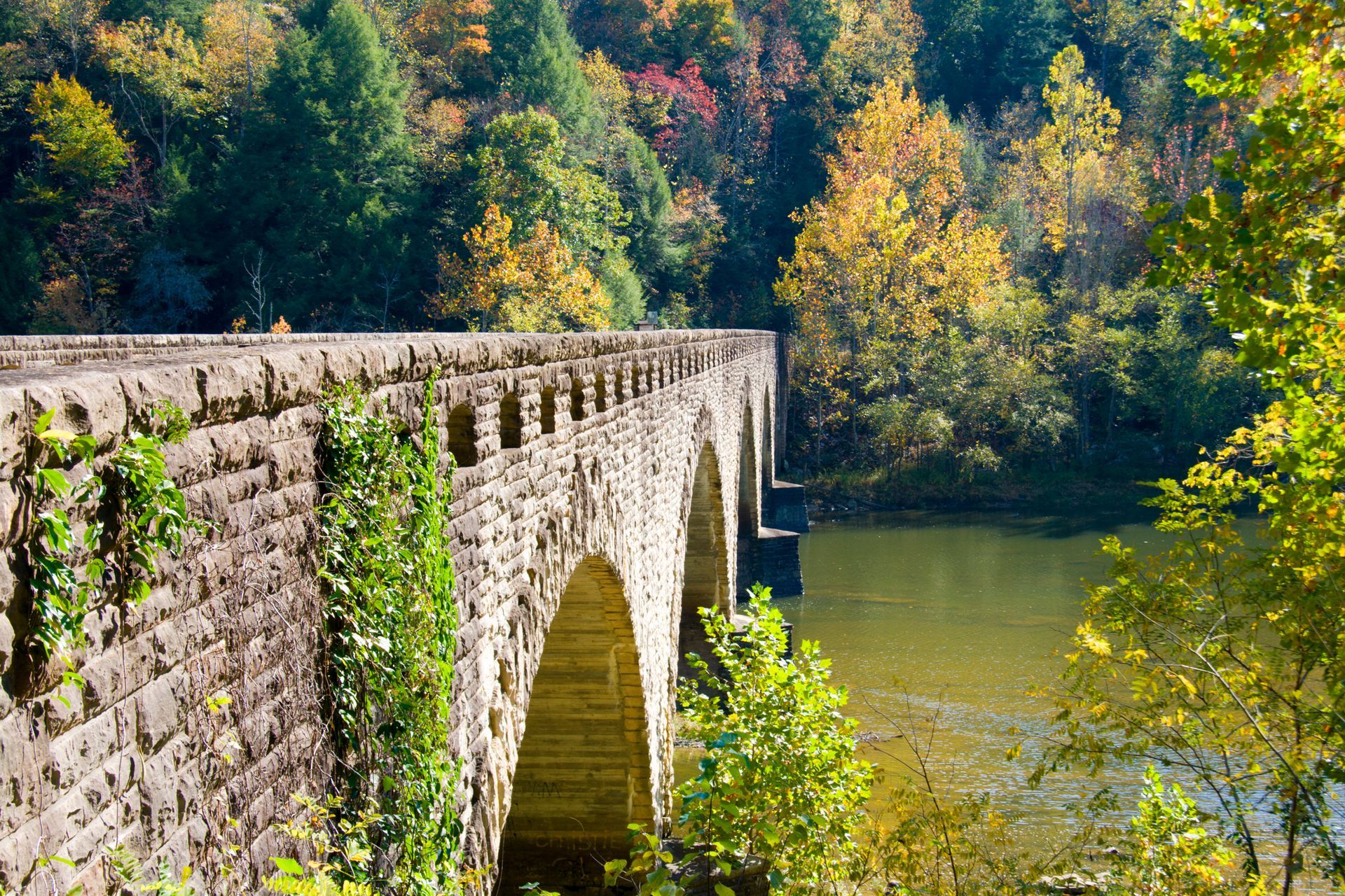 A stone bridge over a river with trees in the background