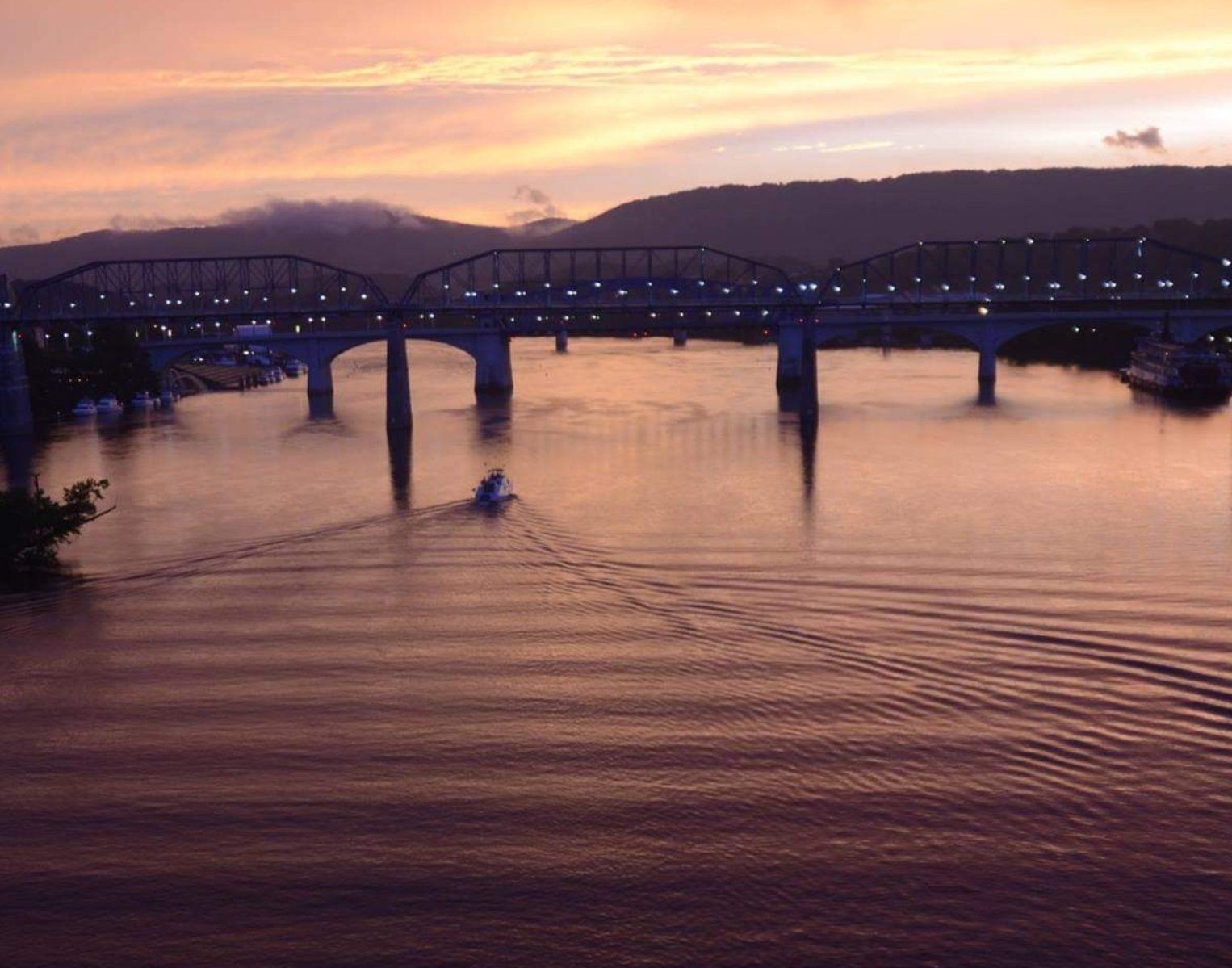 A bridge over a body of water with mountains in the background