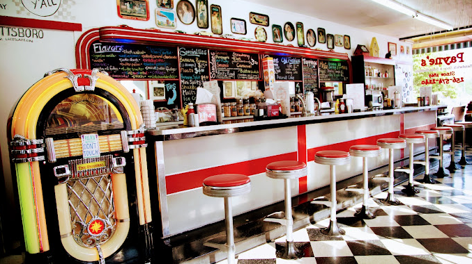 A jukebox is sitting in front of a counter in a diner.