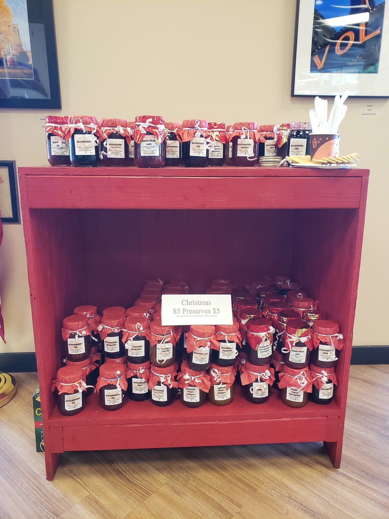 A red shelf with jars of jam on it