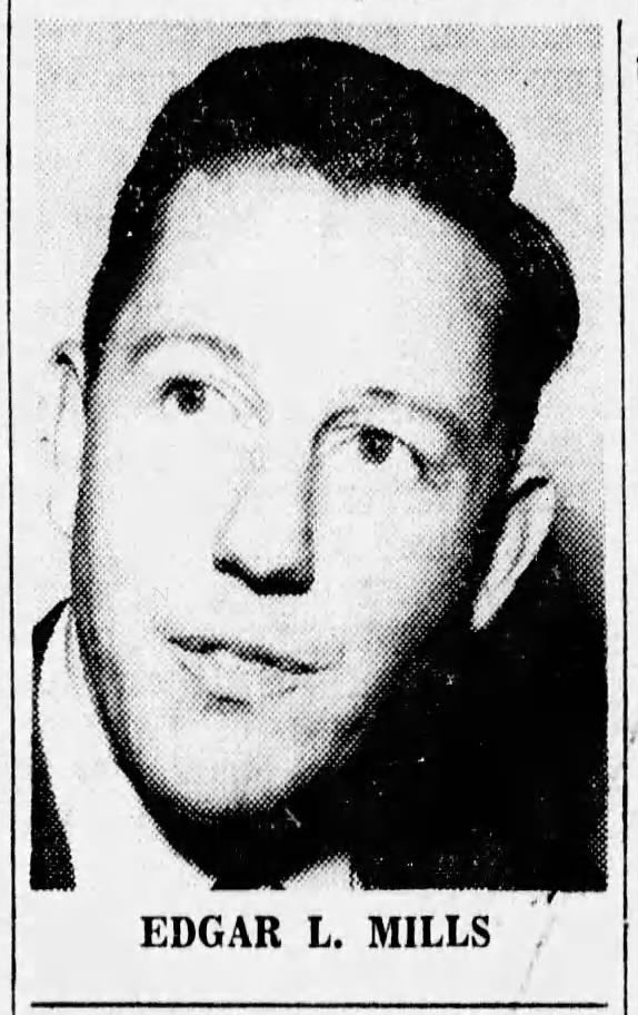 Edgar L. Mills, a man with short, dark hair, looks to the side. He is wearing a dark suit jacket.