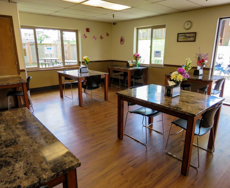 Restaurant dining room with tables, chairs, and fresh flowers on tables.