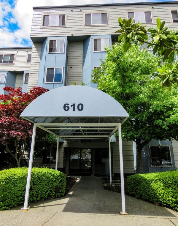 Apartment building with number 610 above entryway, surrounded by greenery.