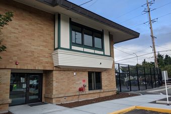 Brick building with windows, a white awning, and a black fence.