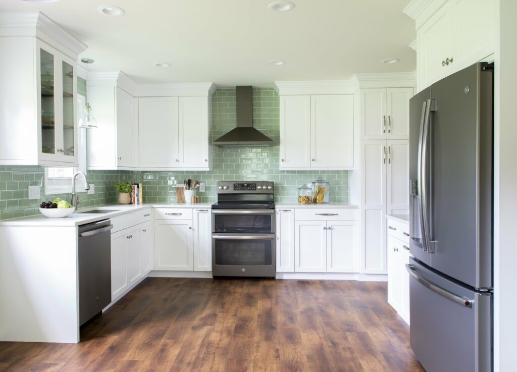 A kitchen with white cabinets , a stove , a refrigerator , and a dishwasher.