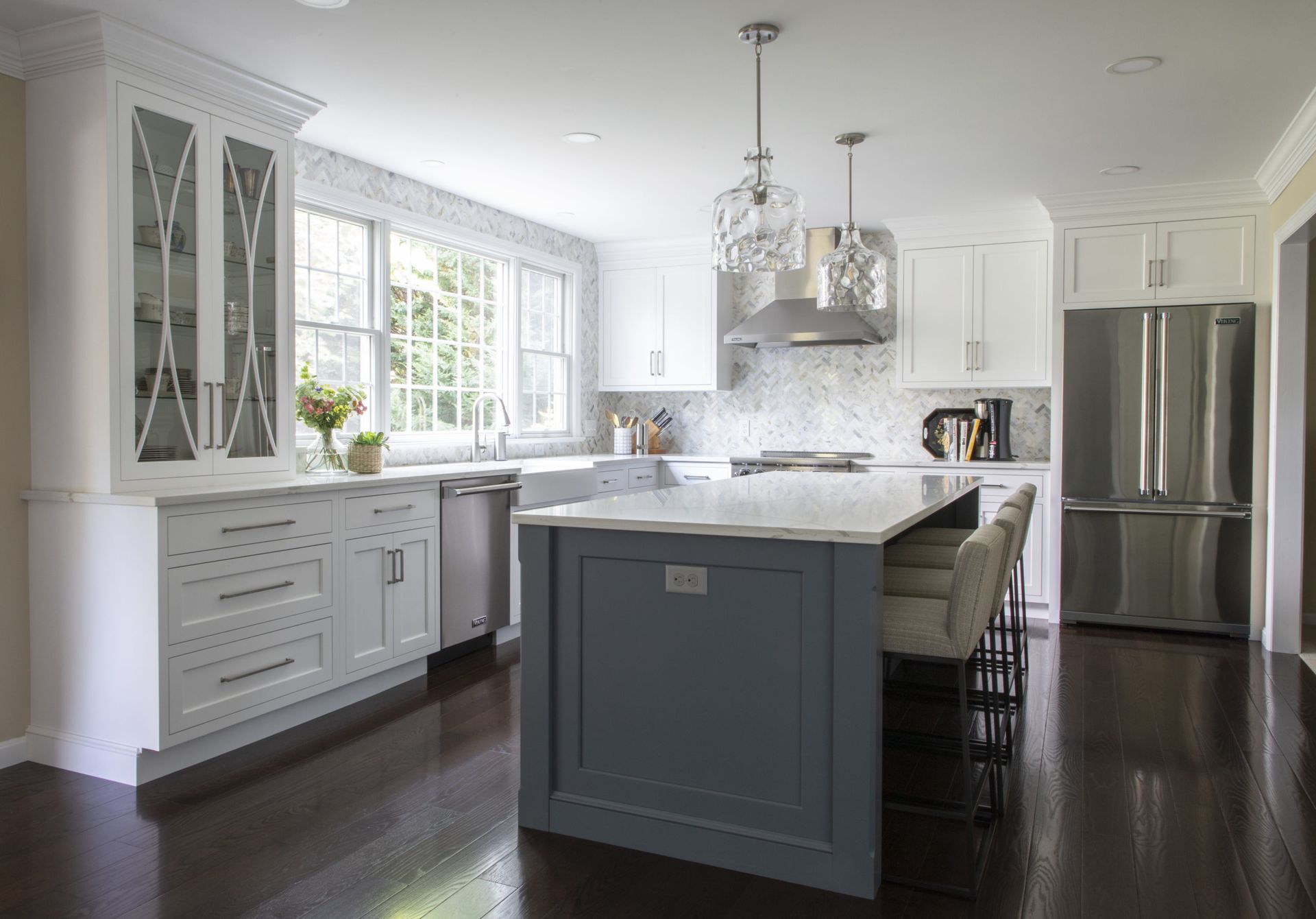 A kitchen with white cabinets and stainless steel appliances and a large island.