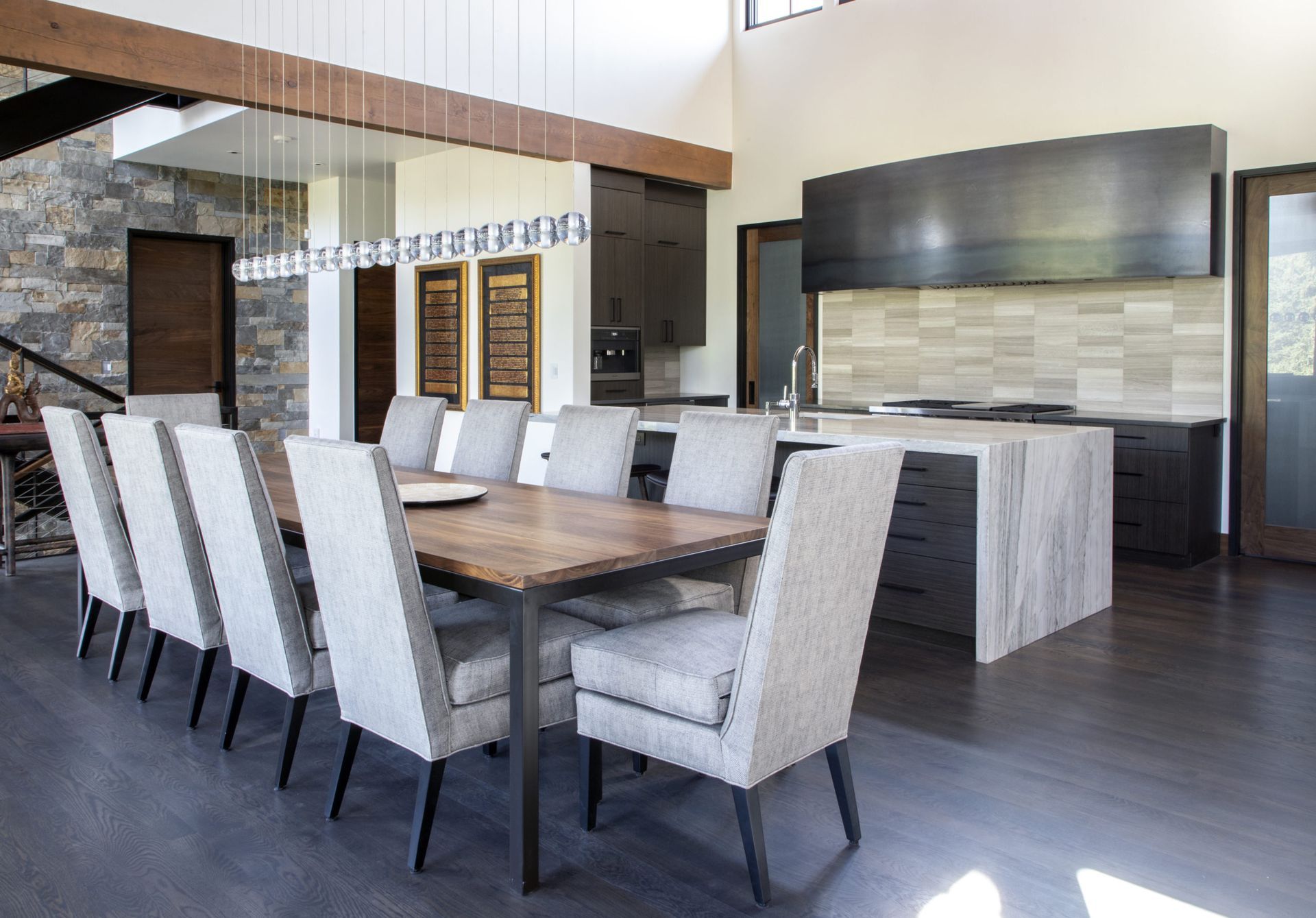 A dining room table with chairs and a kitchen in the background.