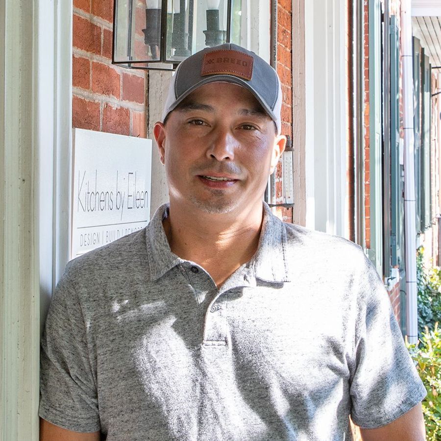 A man wearing a hat is standing in front of a brick building.