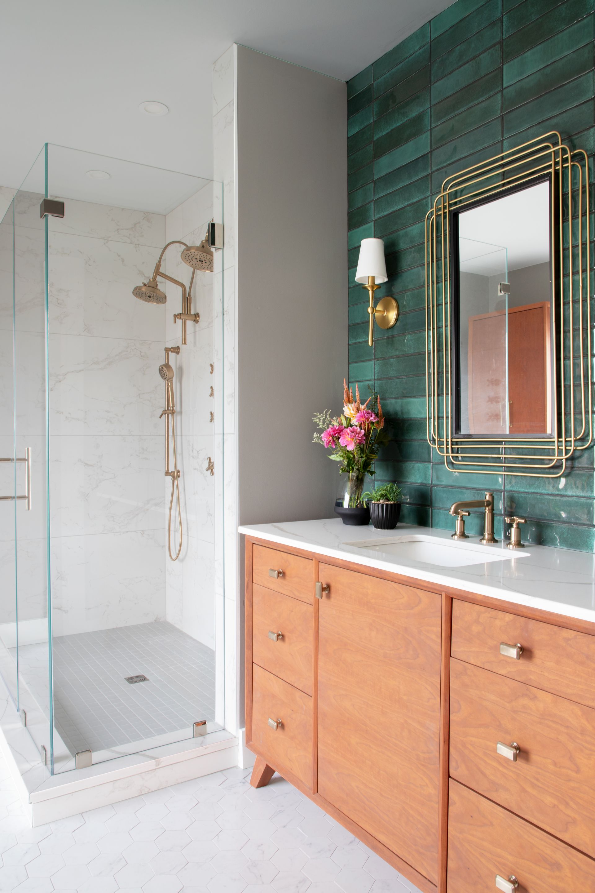 Modern bathroom with glass shower, wooden vanity, and emerald green tiled accent wall.