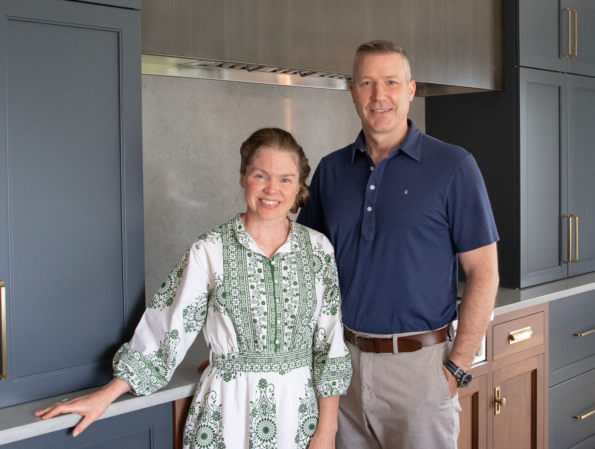 A man and a woman are posing for a picture in a kitchen.