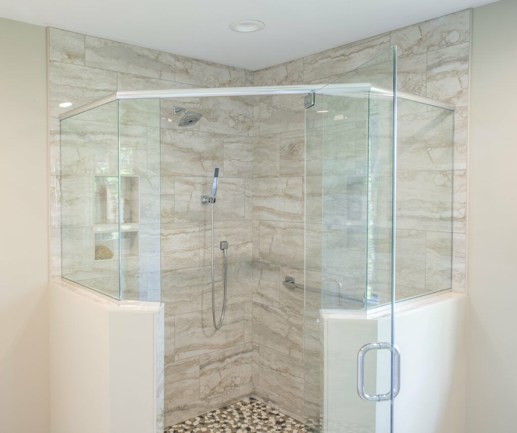 A bathroom with a walk in shower with sliding glass doors.