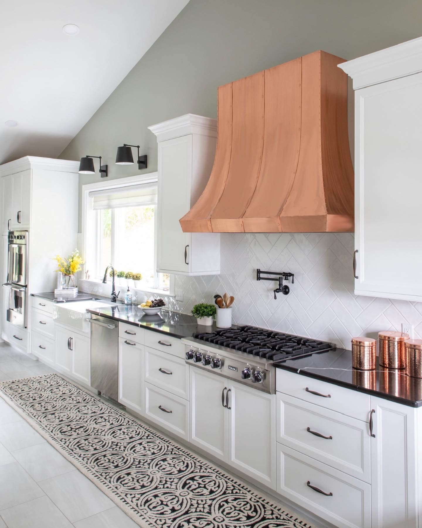 A kitchen with white cabinets and a copper hood