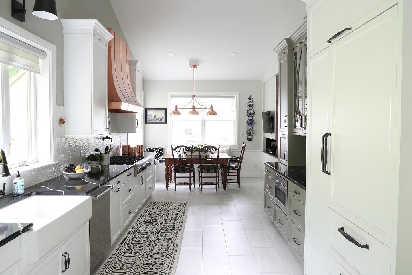 A kitchen with white cabinets and black handles and a dining room in the background.