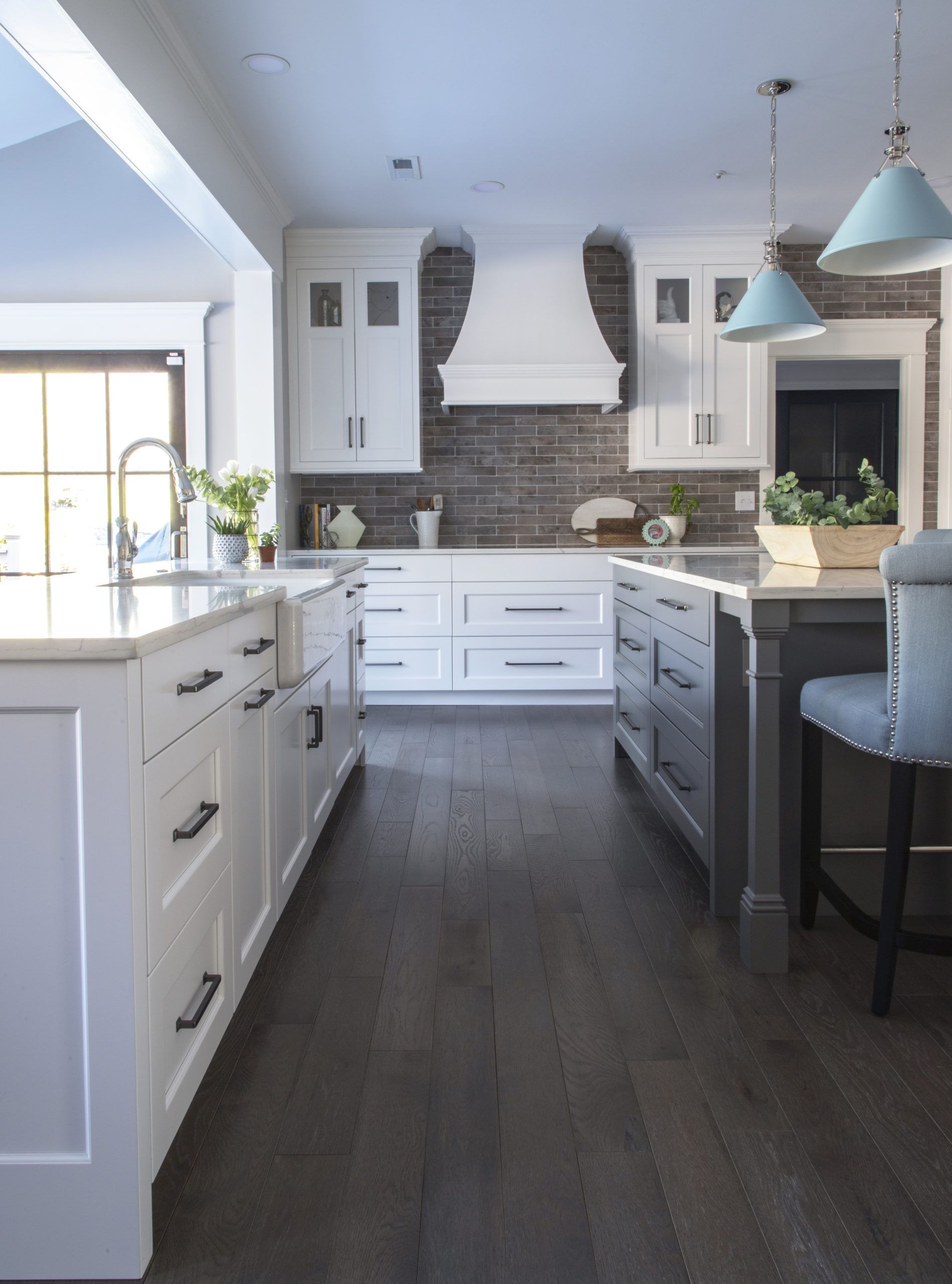 A kitchen with white cabinets and dark wood floors