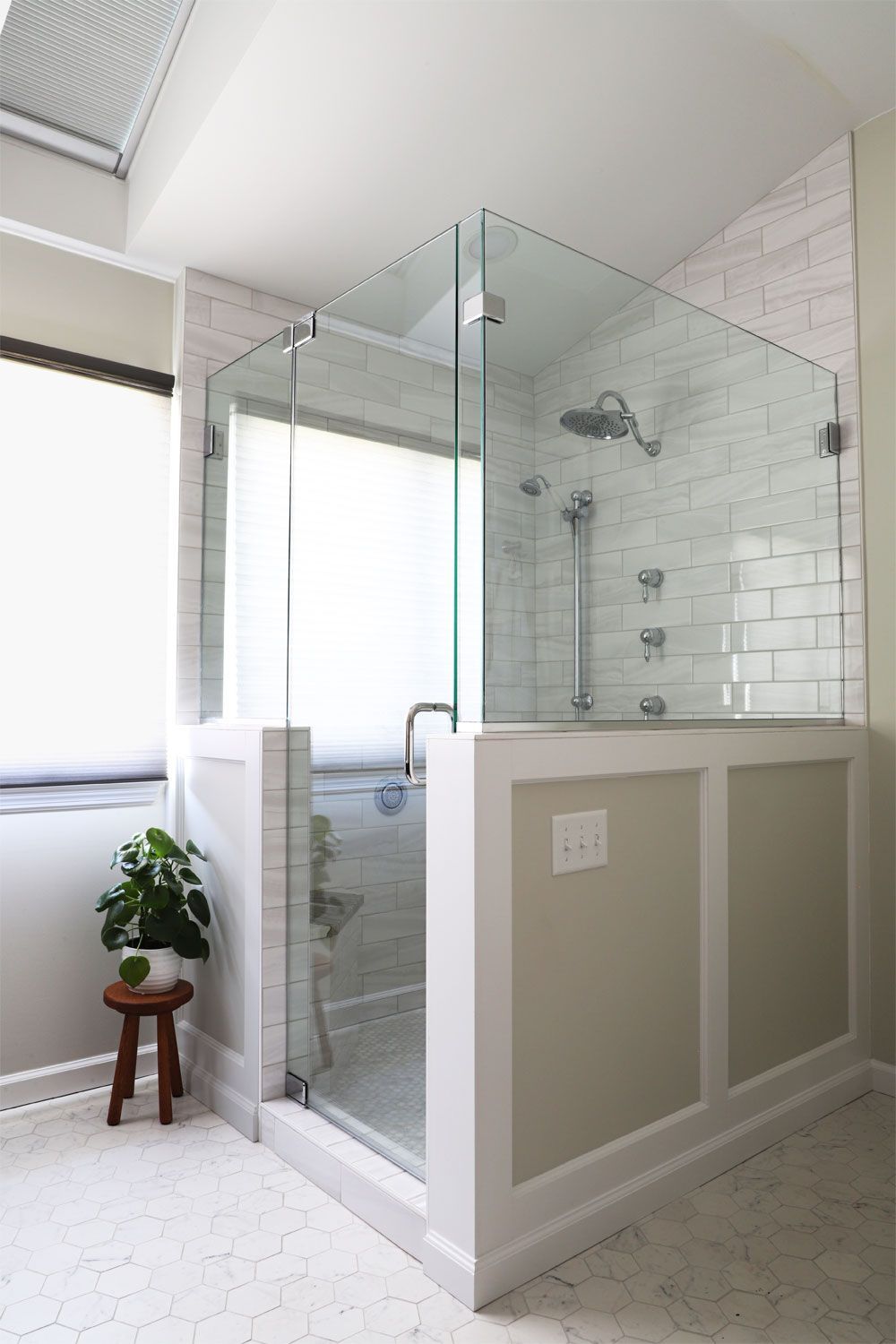 A bathroom with a walk in shower with a glass door.