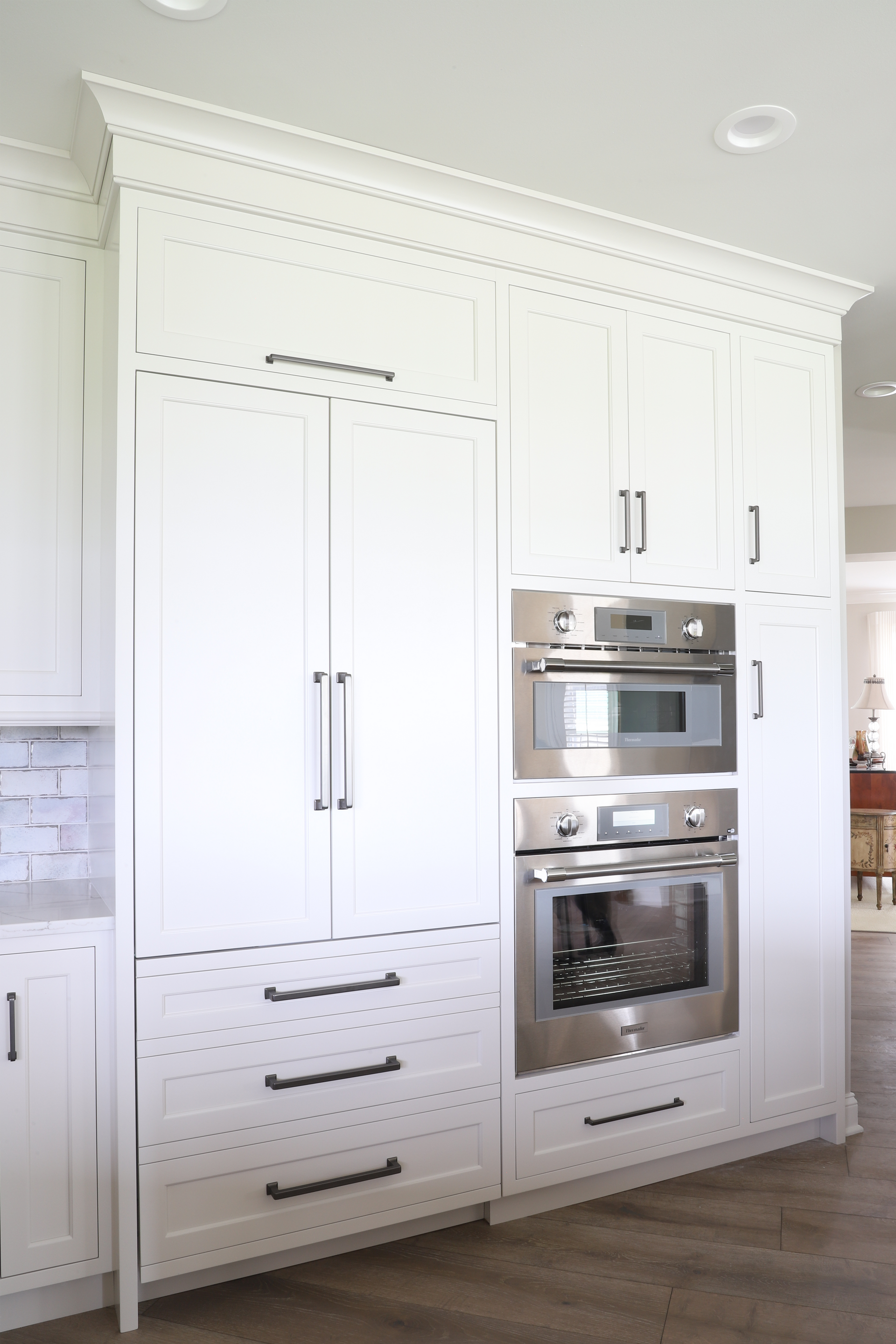 White kitchen cabinets with stainless steel oven and microwave.
