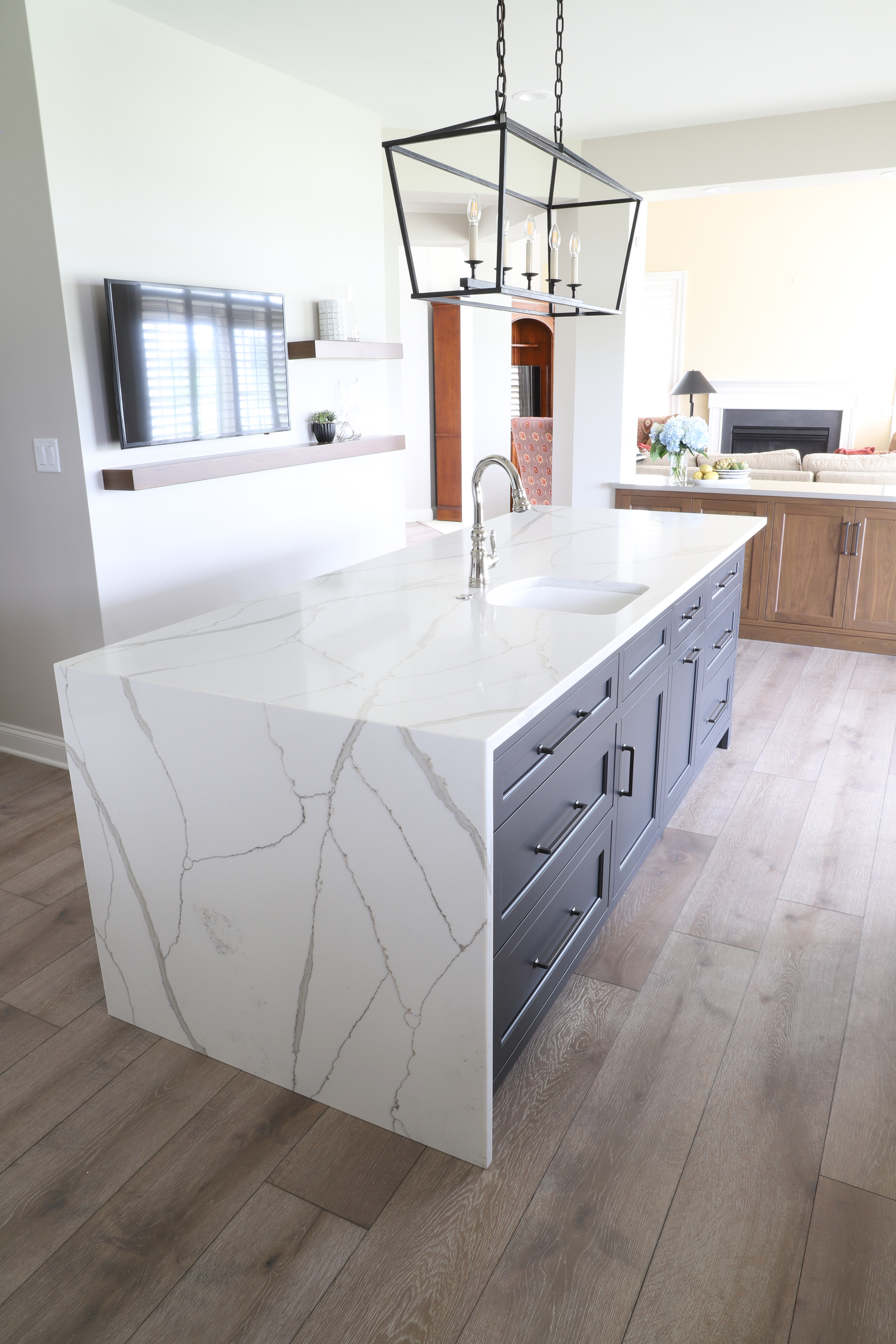 Kitchen island with white marble countertop, dark gray cabinets, and a pendant light.