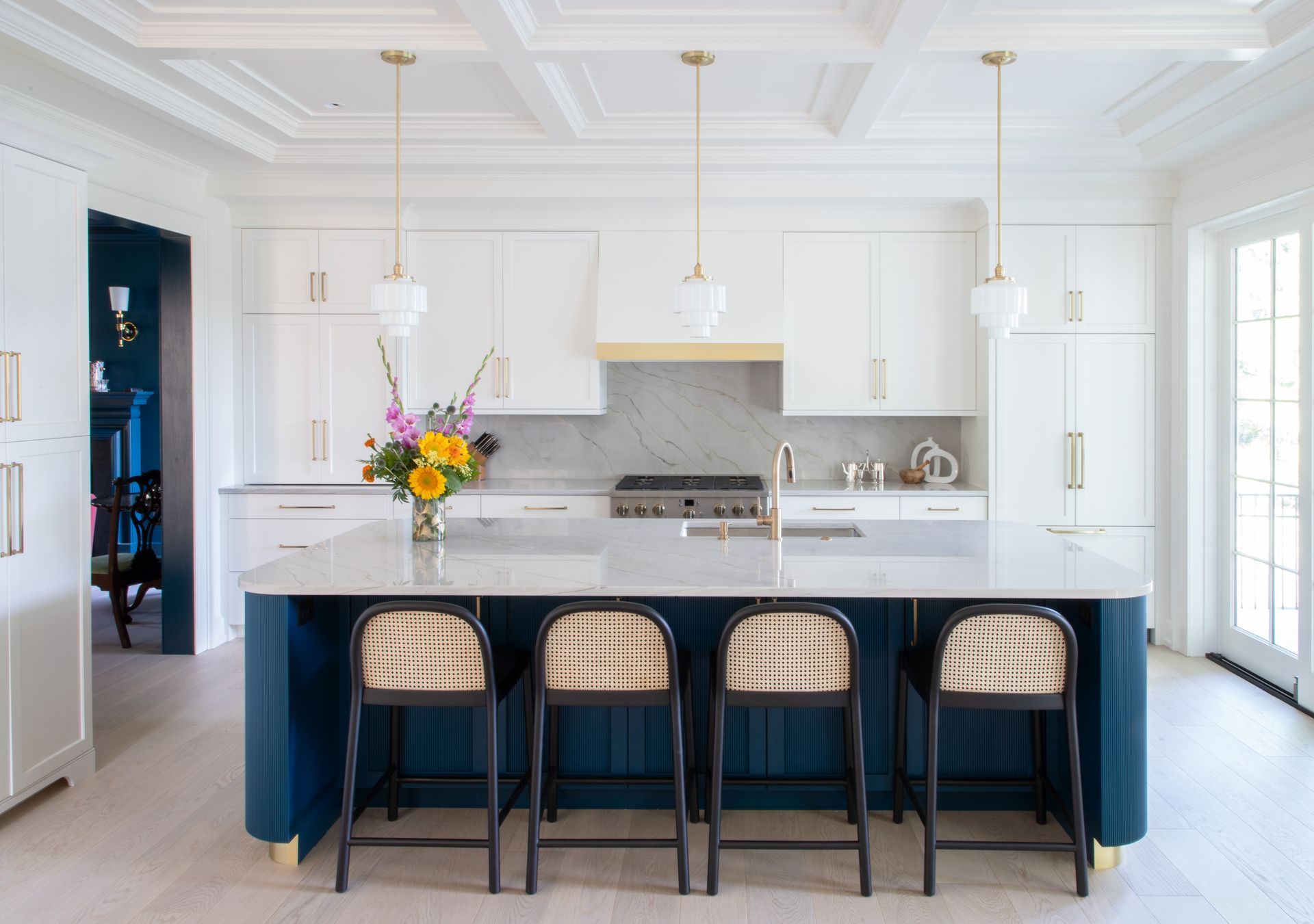 A kitchen with white cabinets and a blue island with stools.