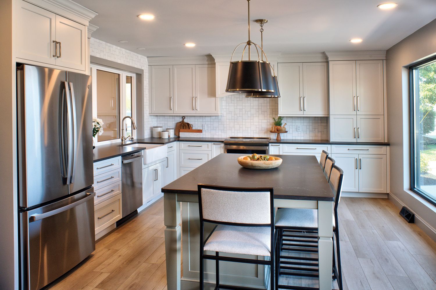 Bright kitchen with white cabinets, stainless steel appliances, and a dark island.