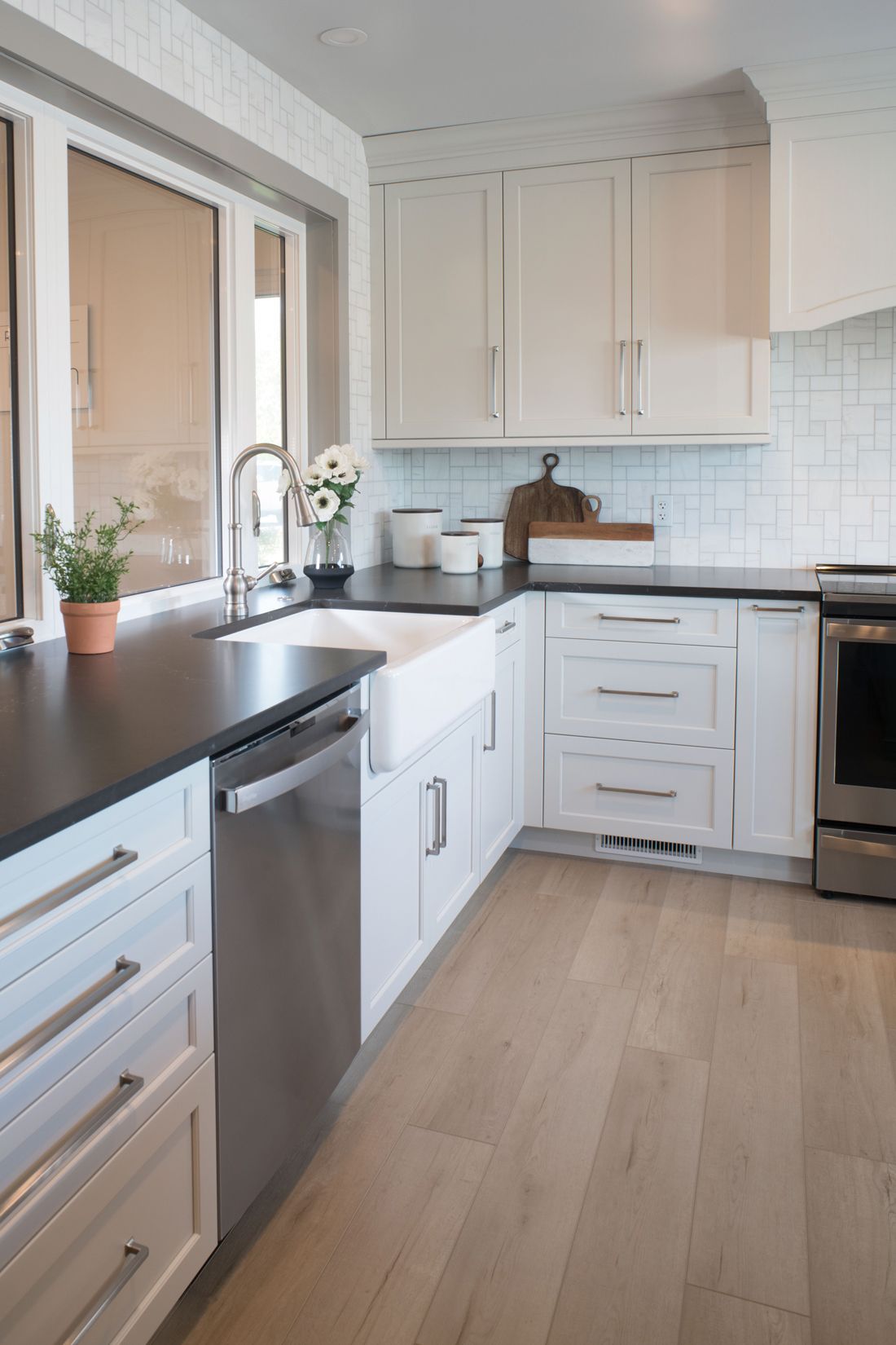 White kitchen with dark countertops and stainless steel appliances with an undermount sink.