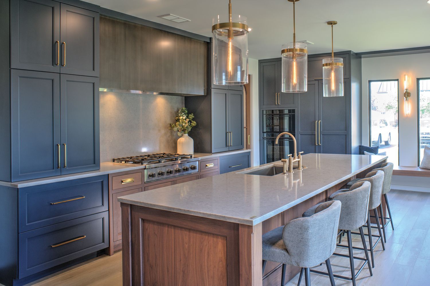 A kitchen with a large island , stove , sink and chairs.