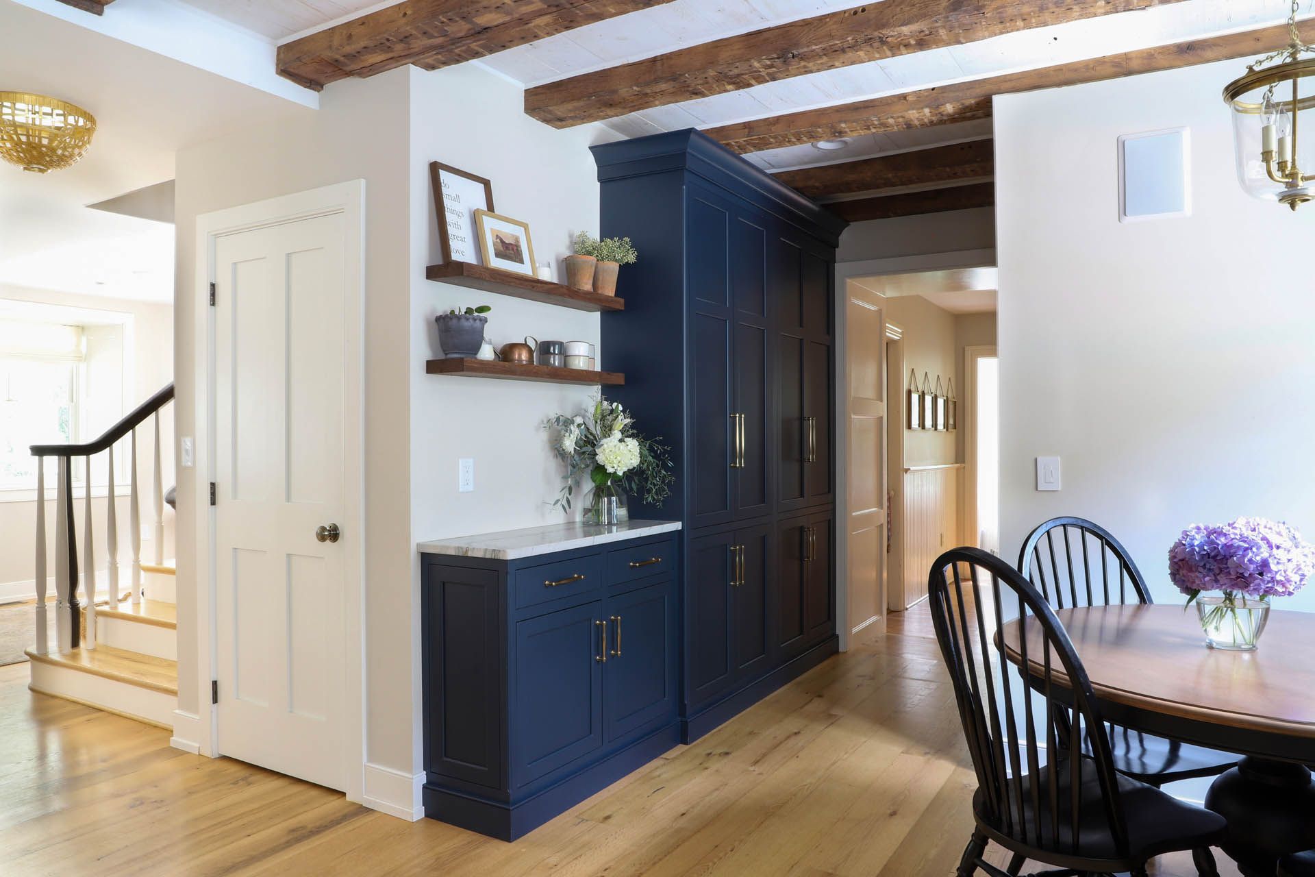 Navy blue cabinet with shelves, built-in against a beige wall, a dining area in a home.