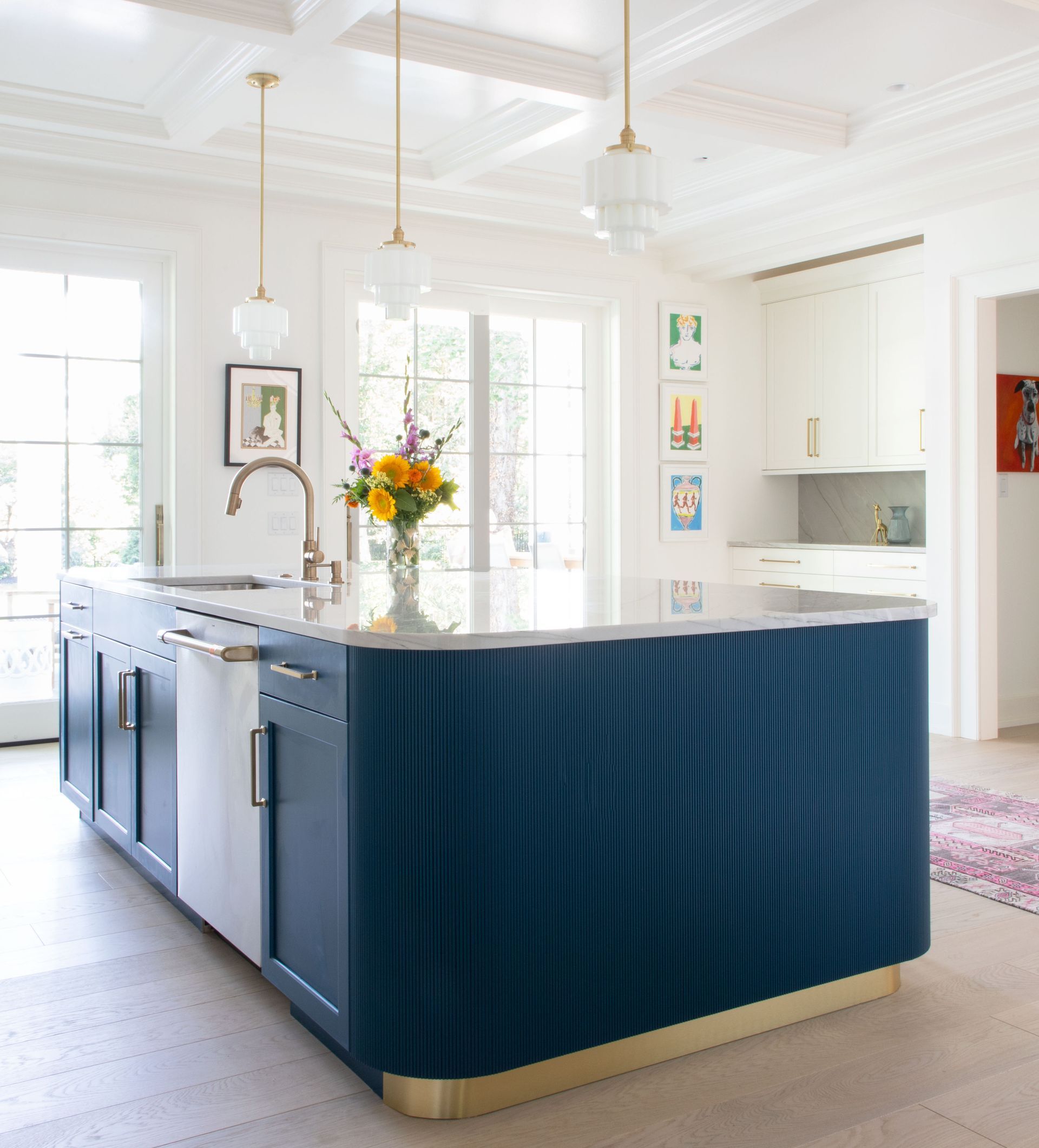 Navy kitchen island with white countertop and gold accents, in a bright kitchen.