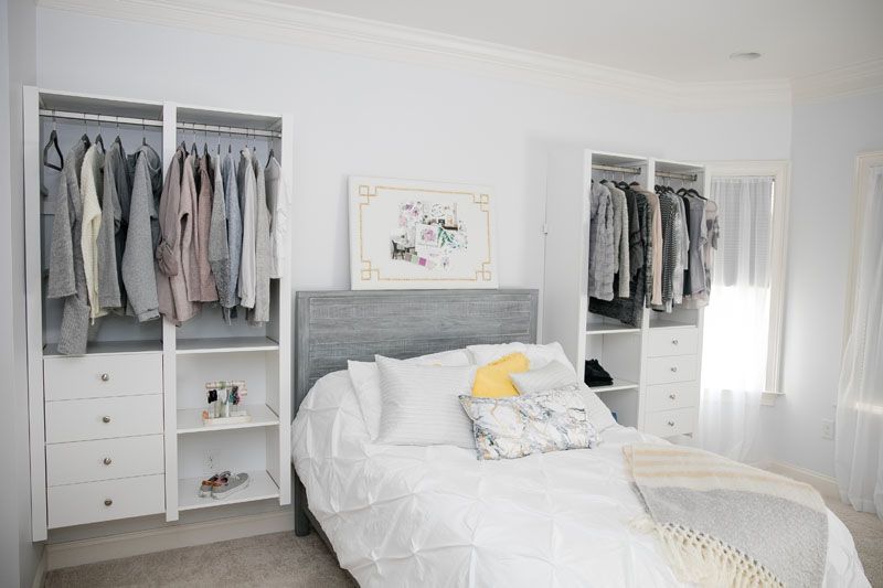 A bedroom with a bed and closets filled with clothes.
