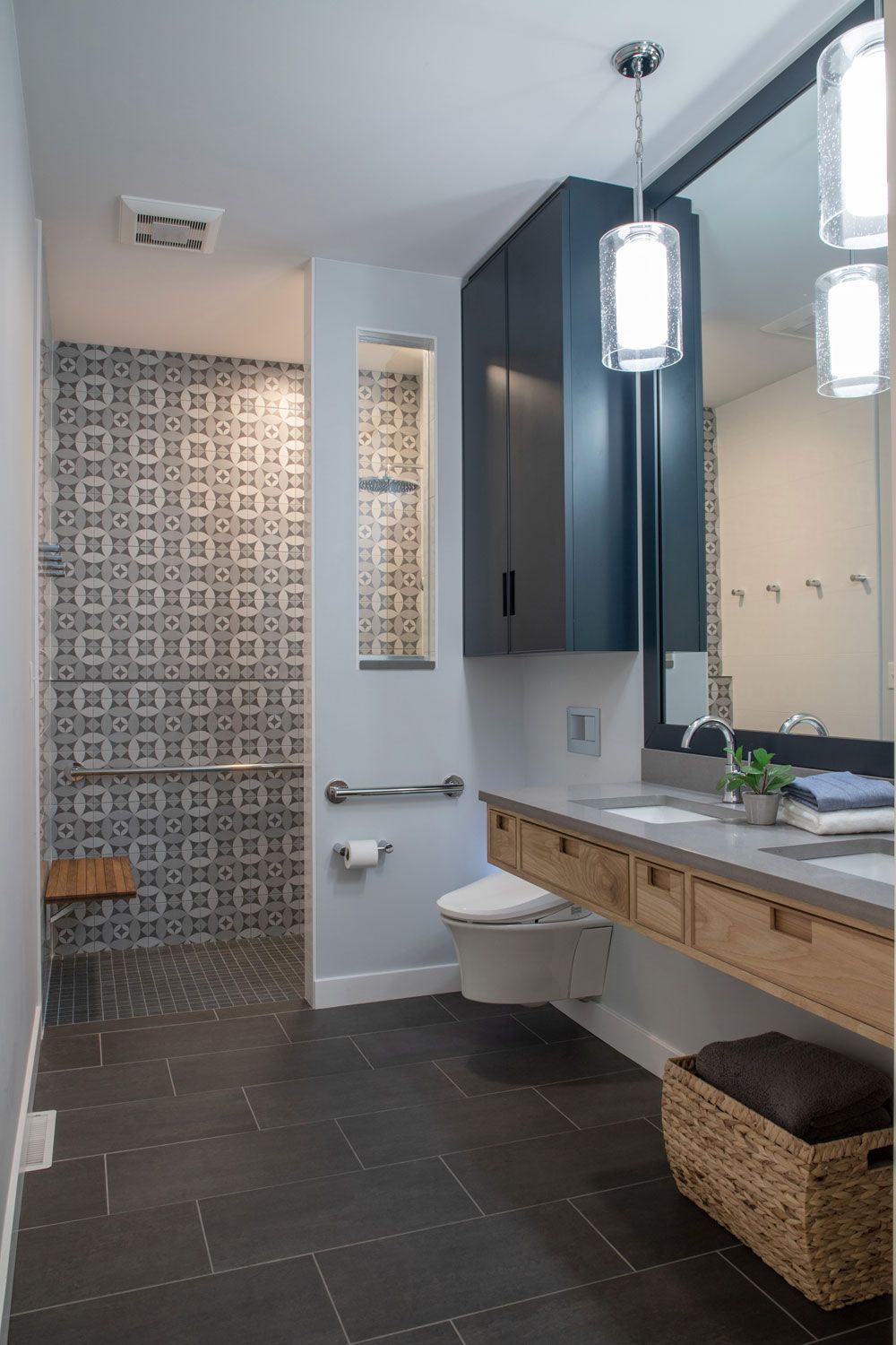 A bathroom with a toilet , sink , mirror and walk in shower.