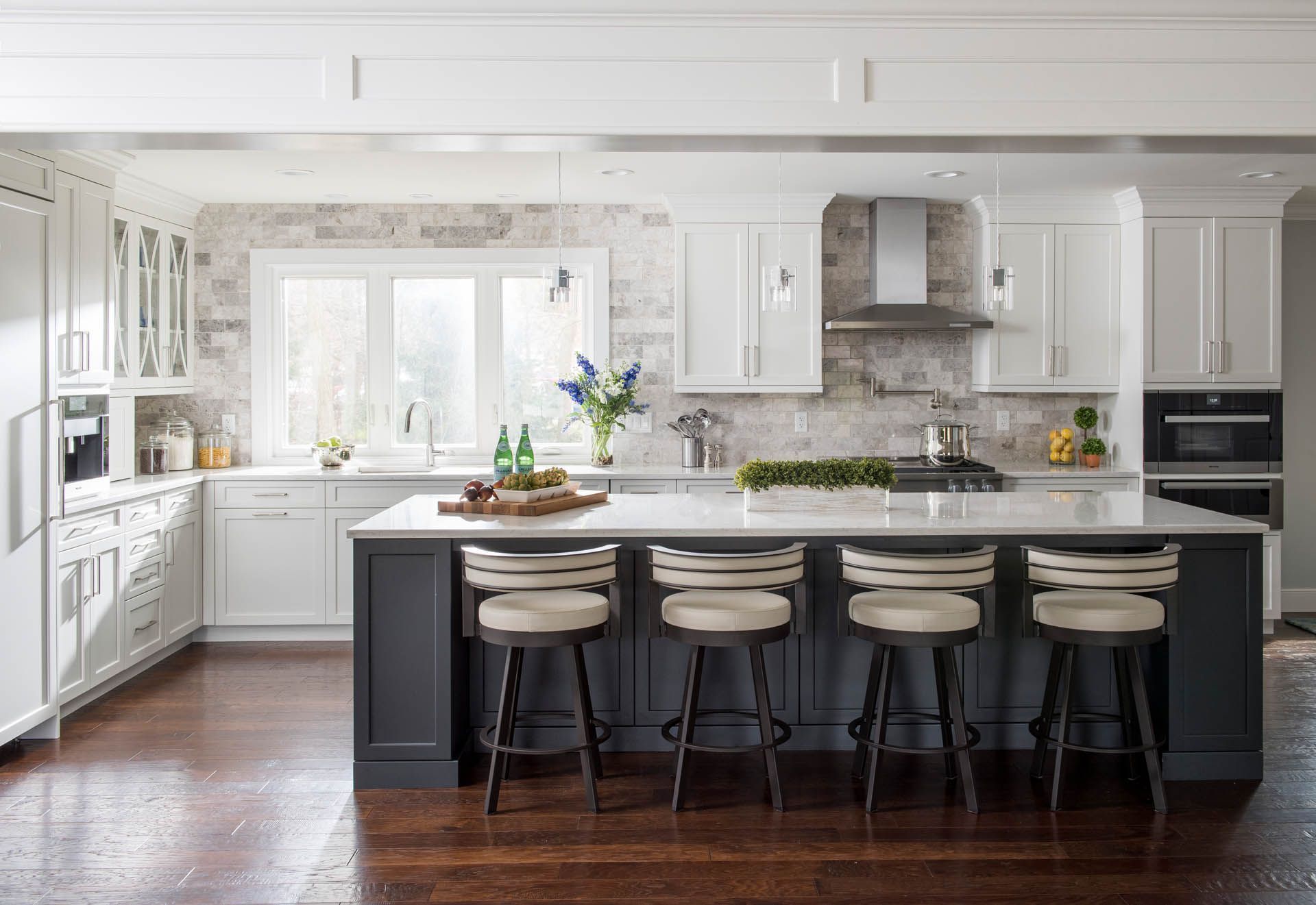 Bright white kitchen with dark island, bar stools, and hardwood floors