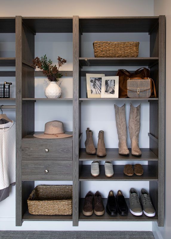 A walk in closet with lots of shelves and drawers filled with shoes and hats.