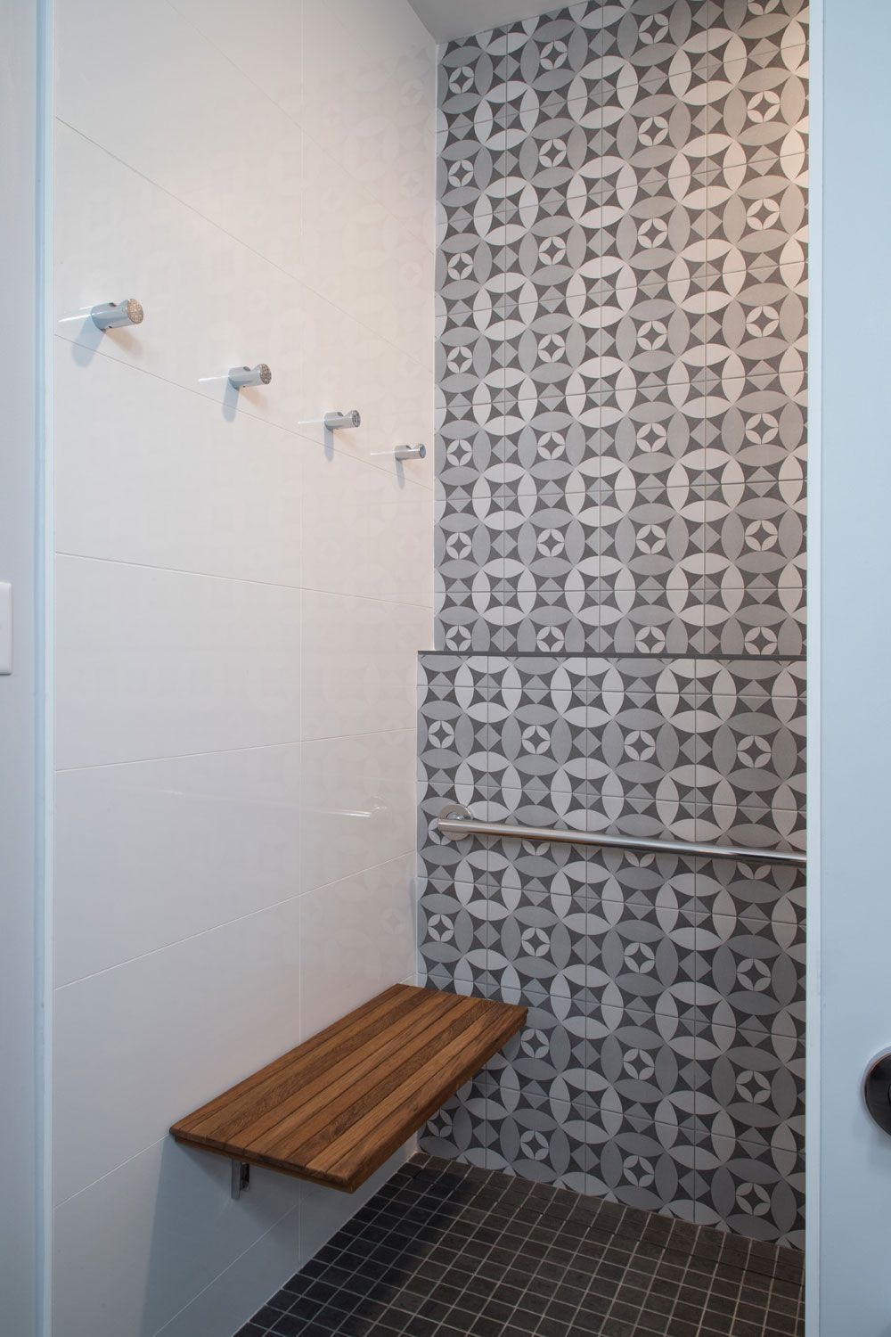A shower with a wooden bench and a patterned wall.