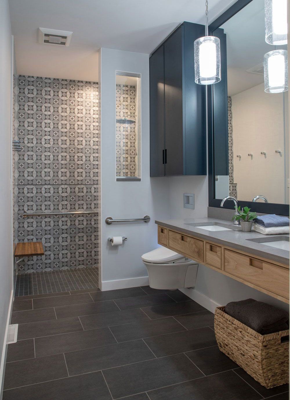 Modern ADA bathroom with patterned shower tile, floating vanity and large mirror for in-law suite.