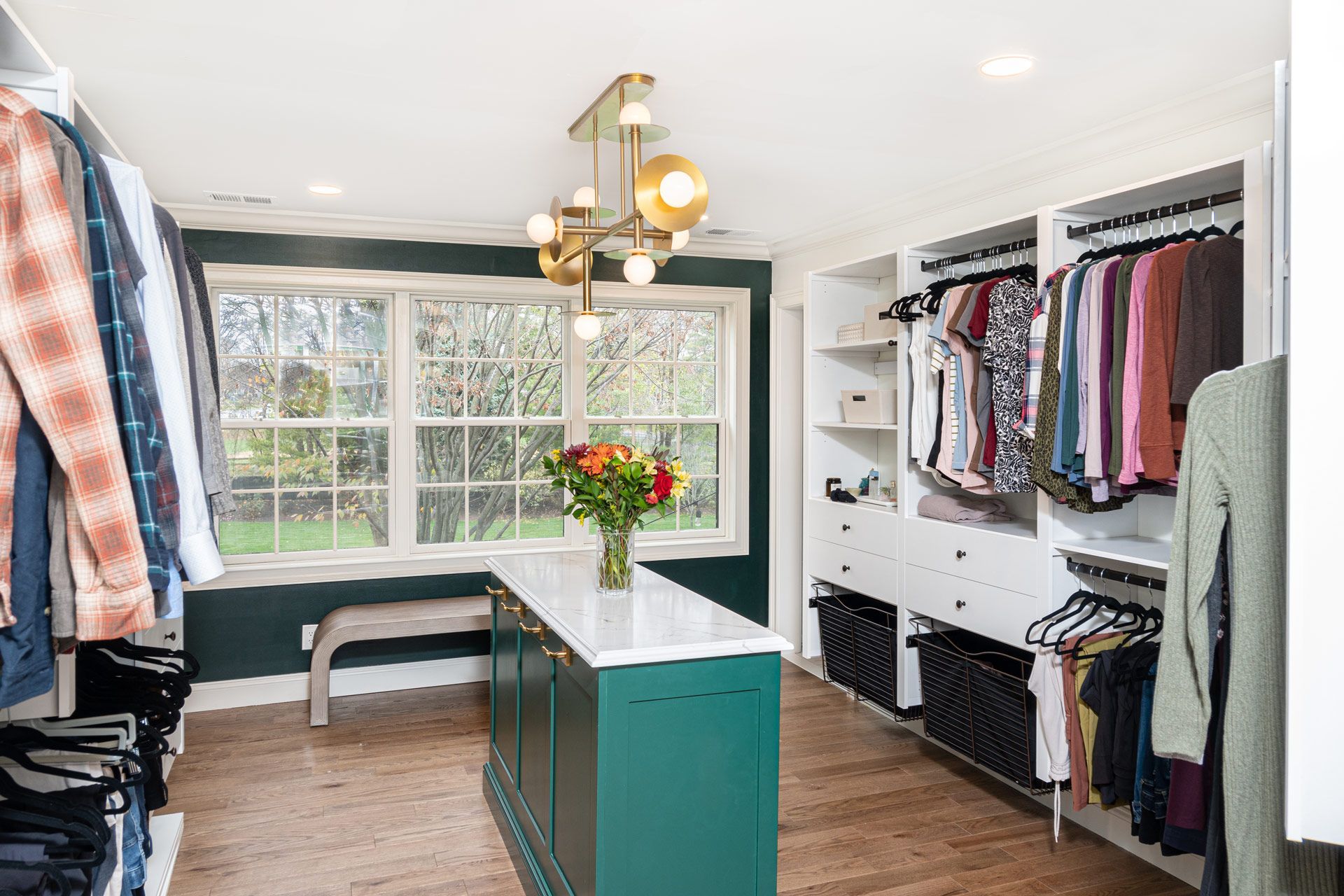 A walk in closet filled with lots of clothes and a vase of flowers.