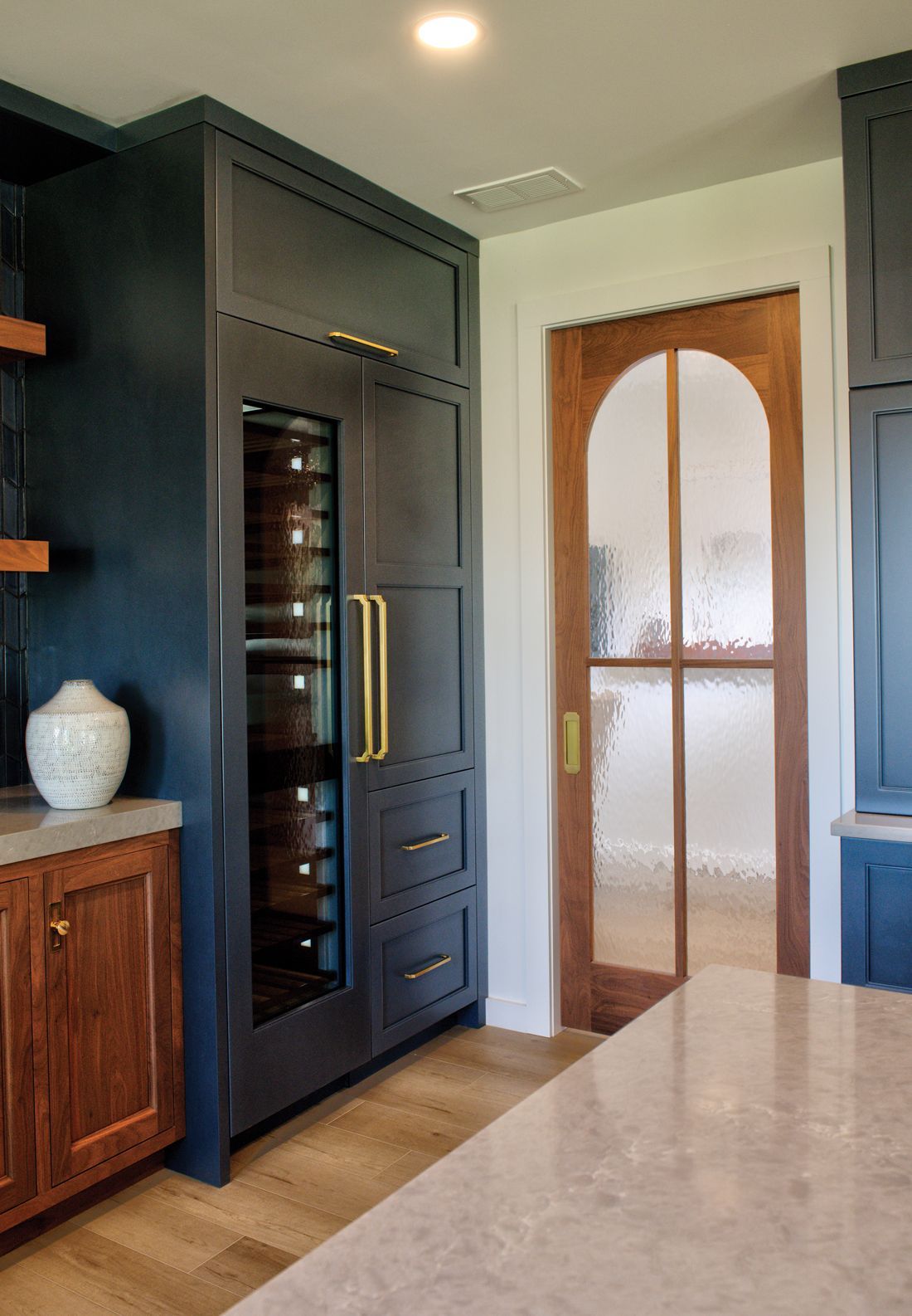 A kitchen with a wine cooler and a glass door.