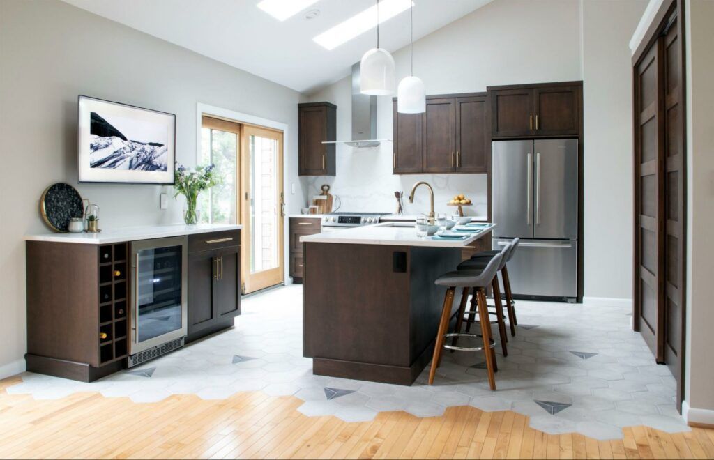 Modern kitchen featuring dark wood cabinets, a stainless steel refrigerator, a center island with stools, and tile flooring.