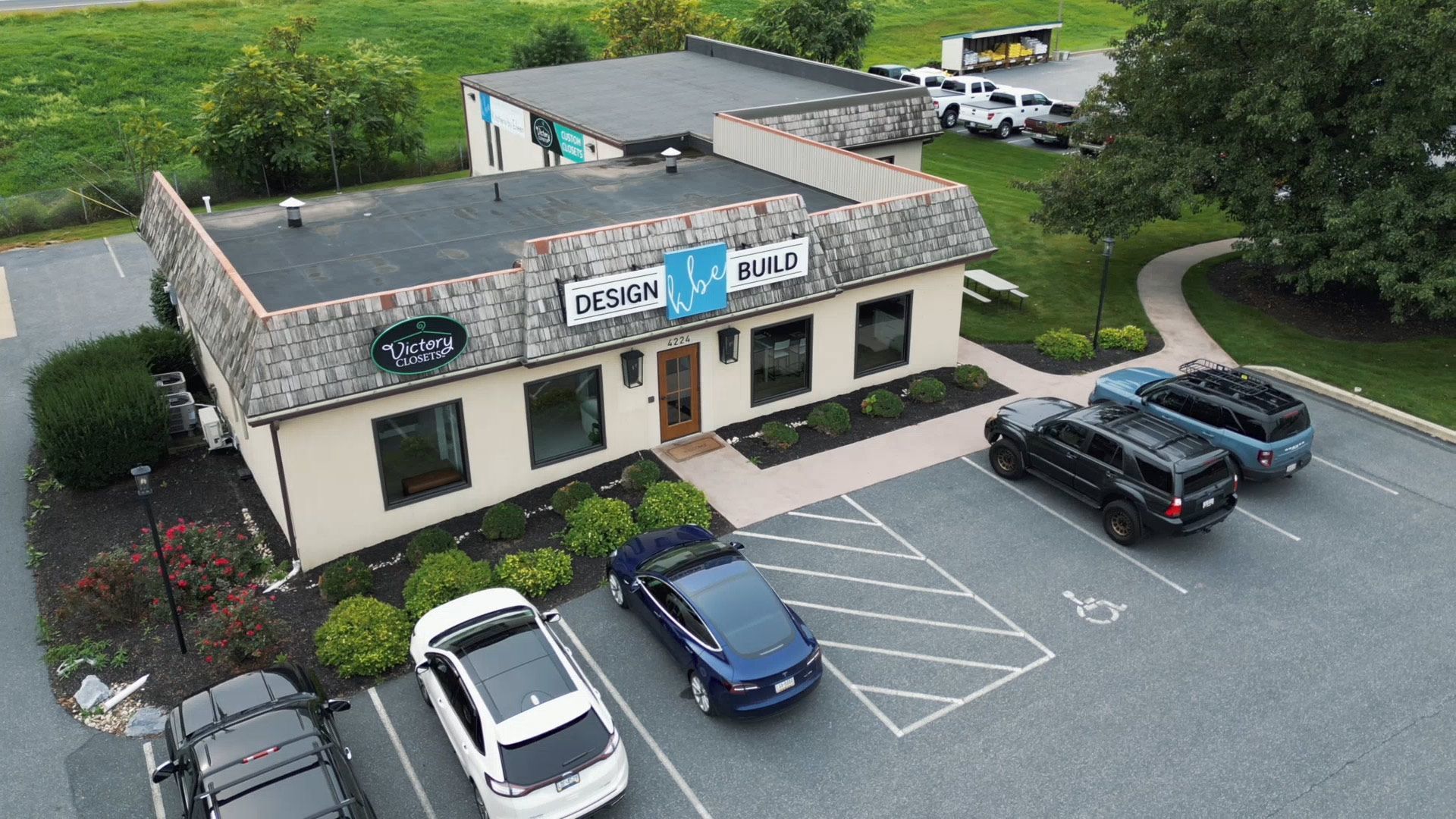 Aerial view of KBE Build's showroom in Brownstown with parked cars and a sign over the entrance.