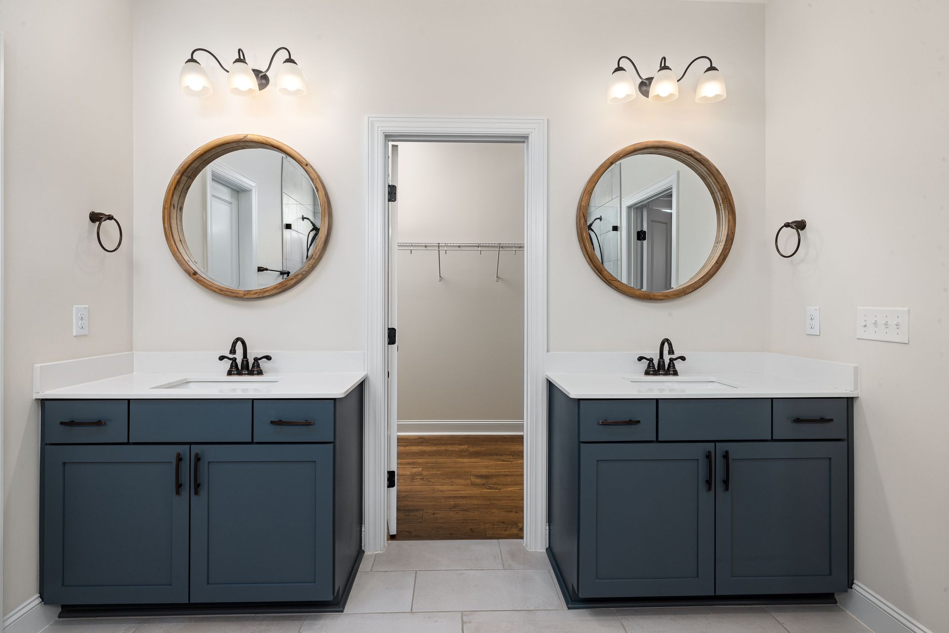 Double vanity bathroom with dark blue cabinets, round mirrors, and white walls.