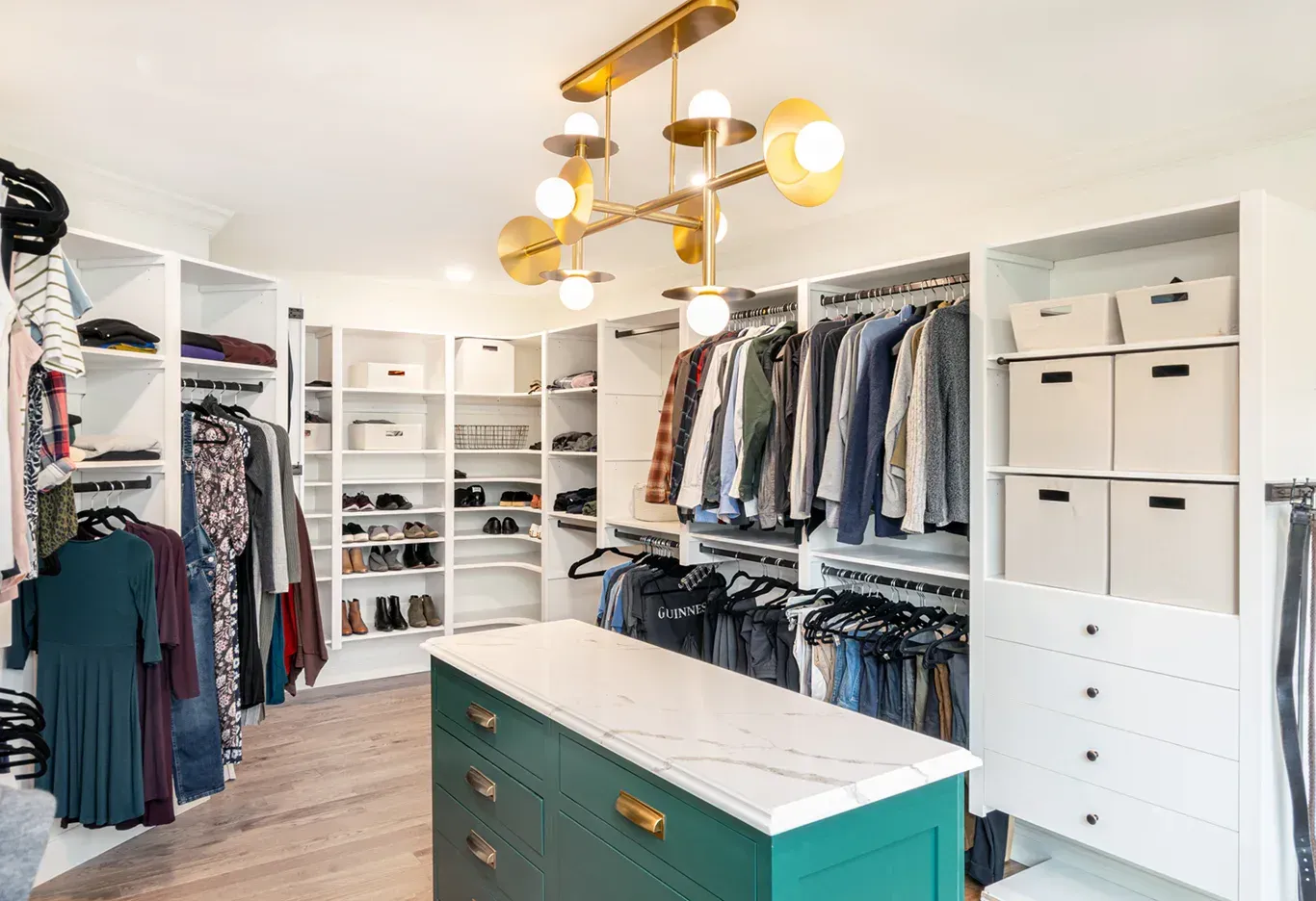 A walk in closet filled with lots of clothes and drawers.