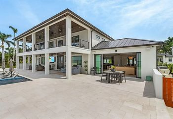 Two-story modern home with balconies and a patio. The exterior is white with a dark roof.