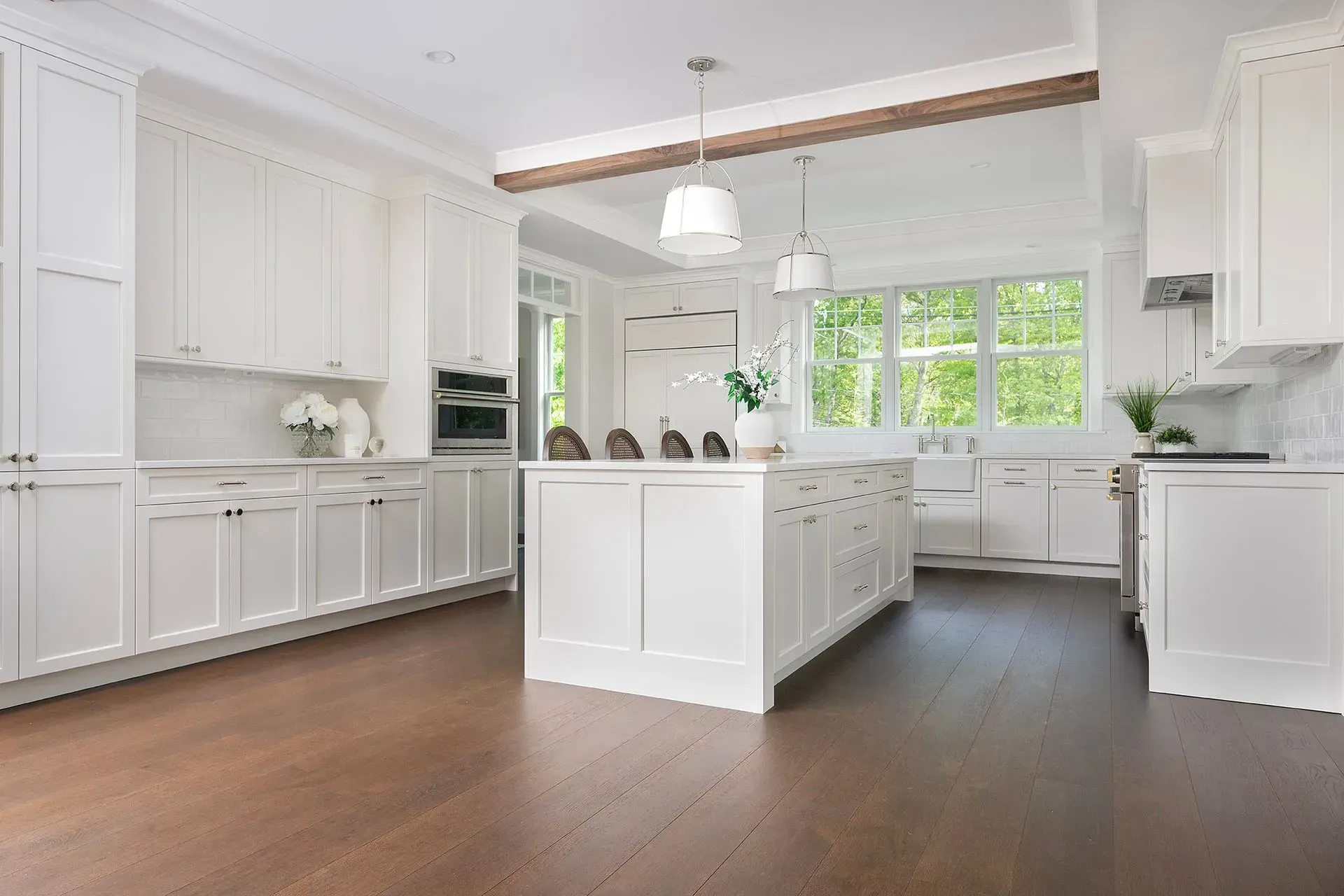 Bright white kitchen with island, cabinets, and dark wood floors.