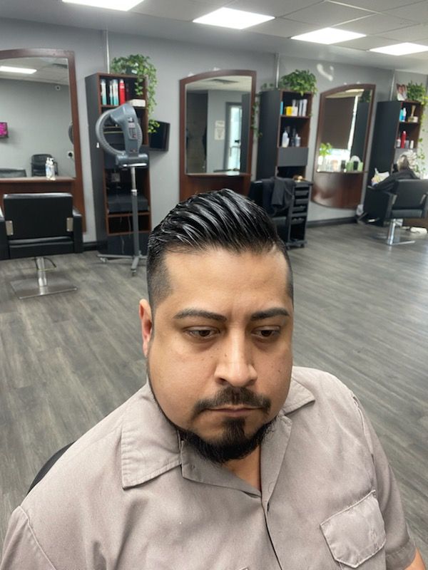 A man with a beard is getting his hair cut in a salon